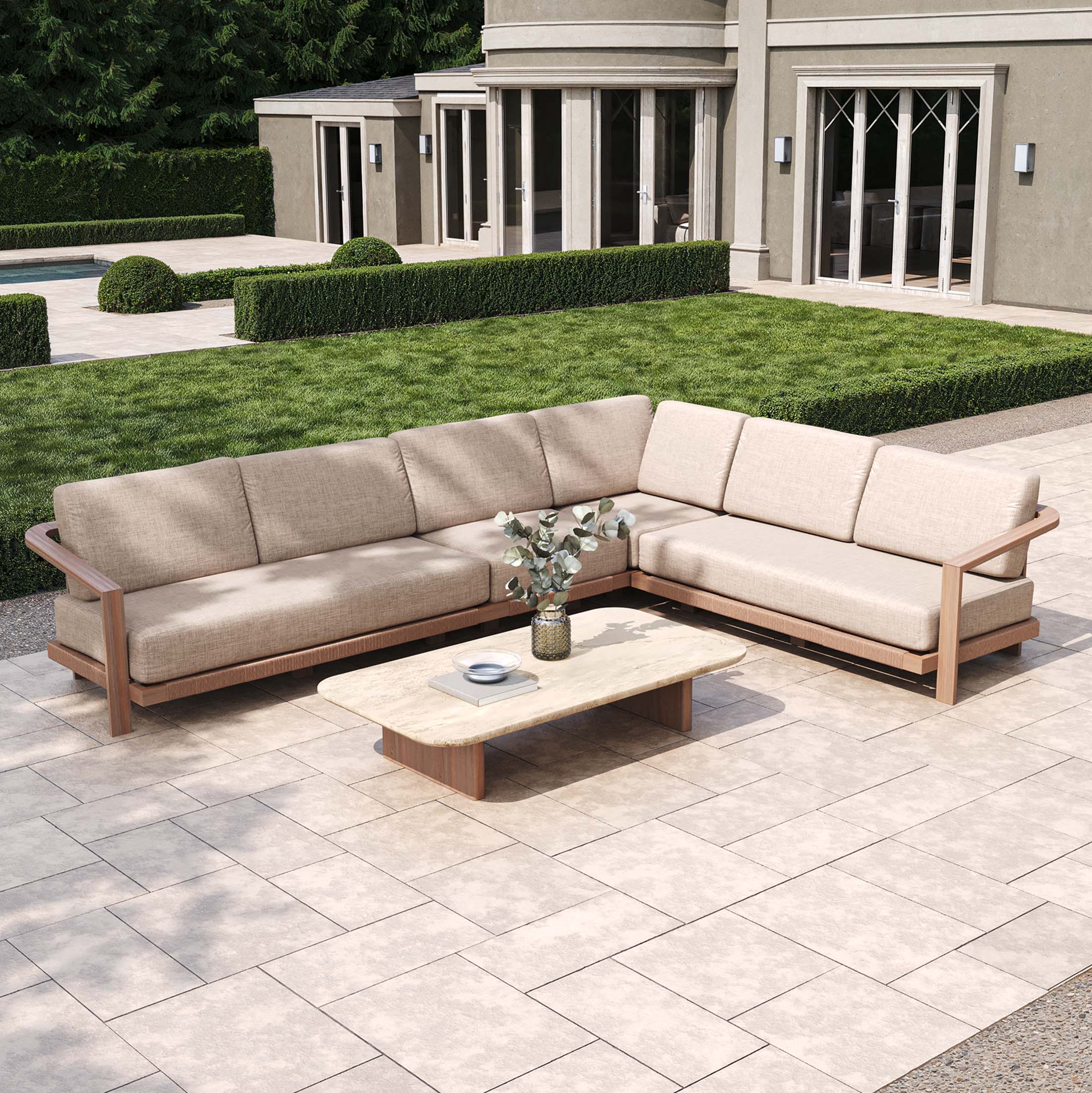 The outdoor patio showcases the Tivoli Large Corner Set with a Marble Coffee Table in Fawn, surrounded by lush hedges near a modern building.