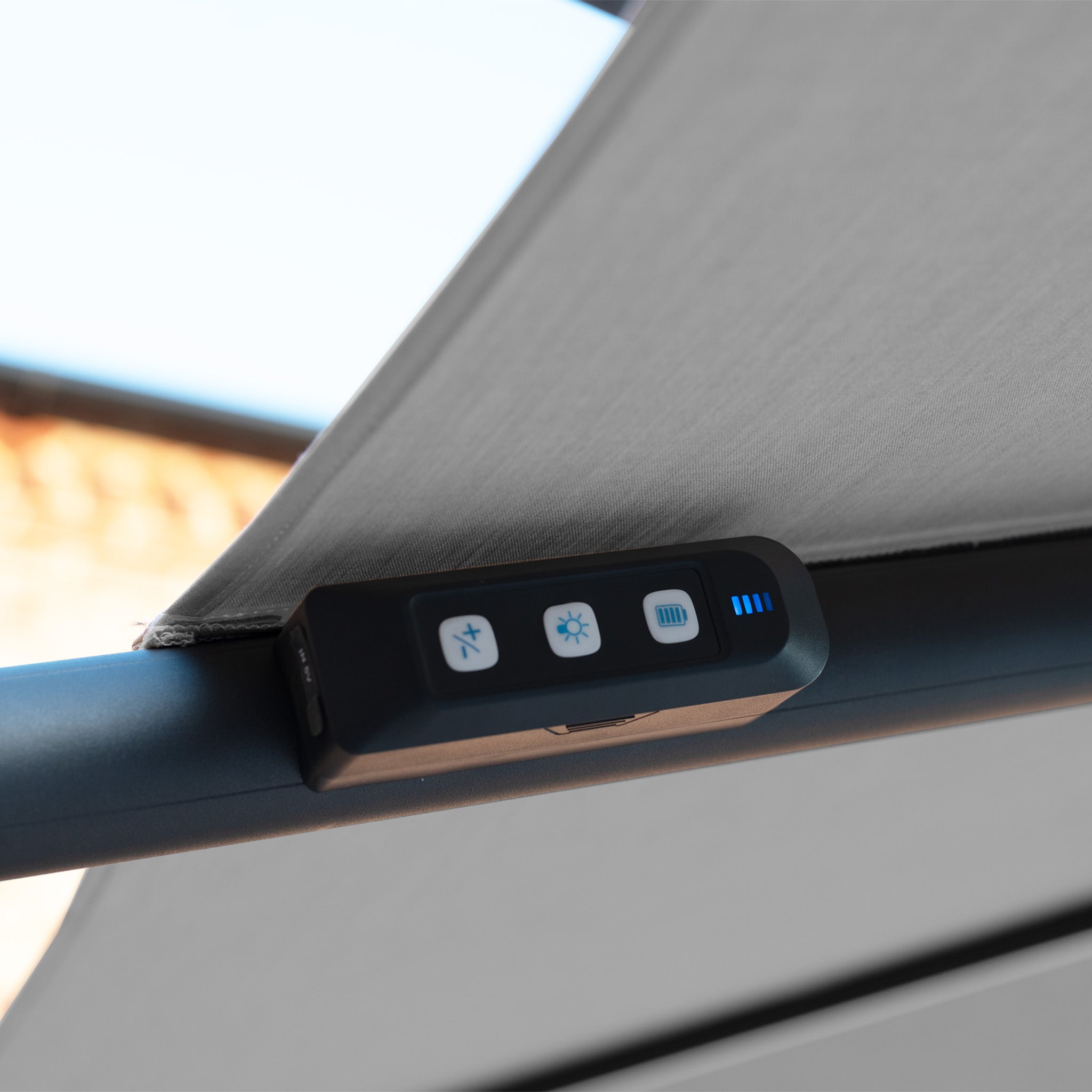 Close-up of the Volos 3m x 4m Rectangular Cantilever Parasol in Slate, showing a remote control with four buttons and blue LED lights, attached to its UV resistant canopy and sturdy 120kg granite base.