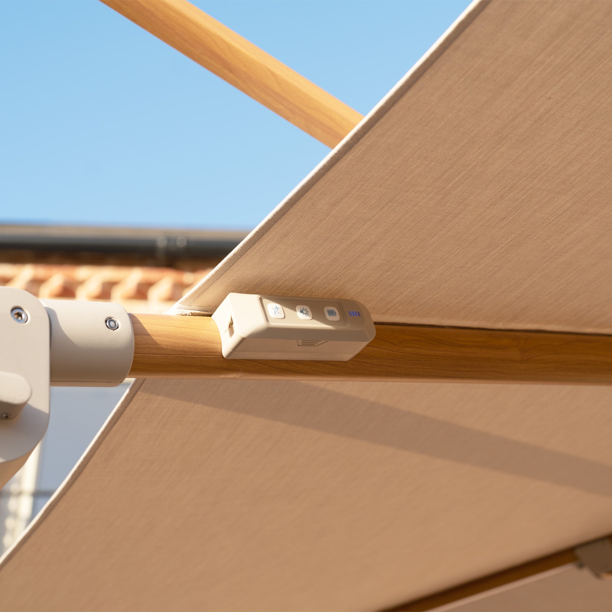 Close-up of the Volos 3m x 4m Rectangular Cantilever Parasol’s control panel on a wood effect frame under a UV resistant wheat canopy, with LED lighting and a 120kg granite base, set against a blue sky.