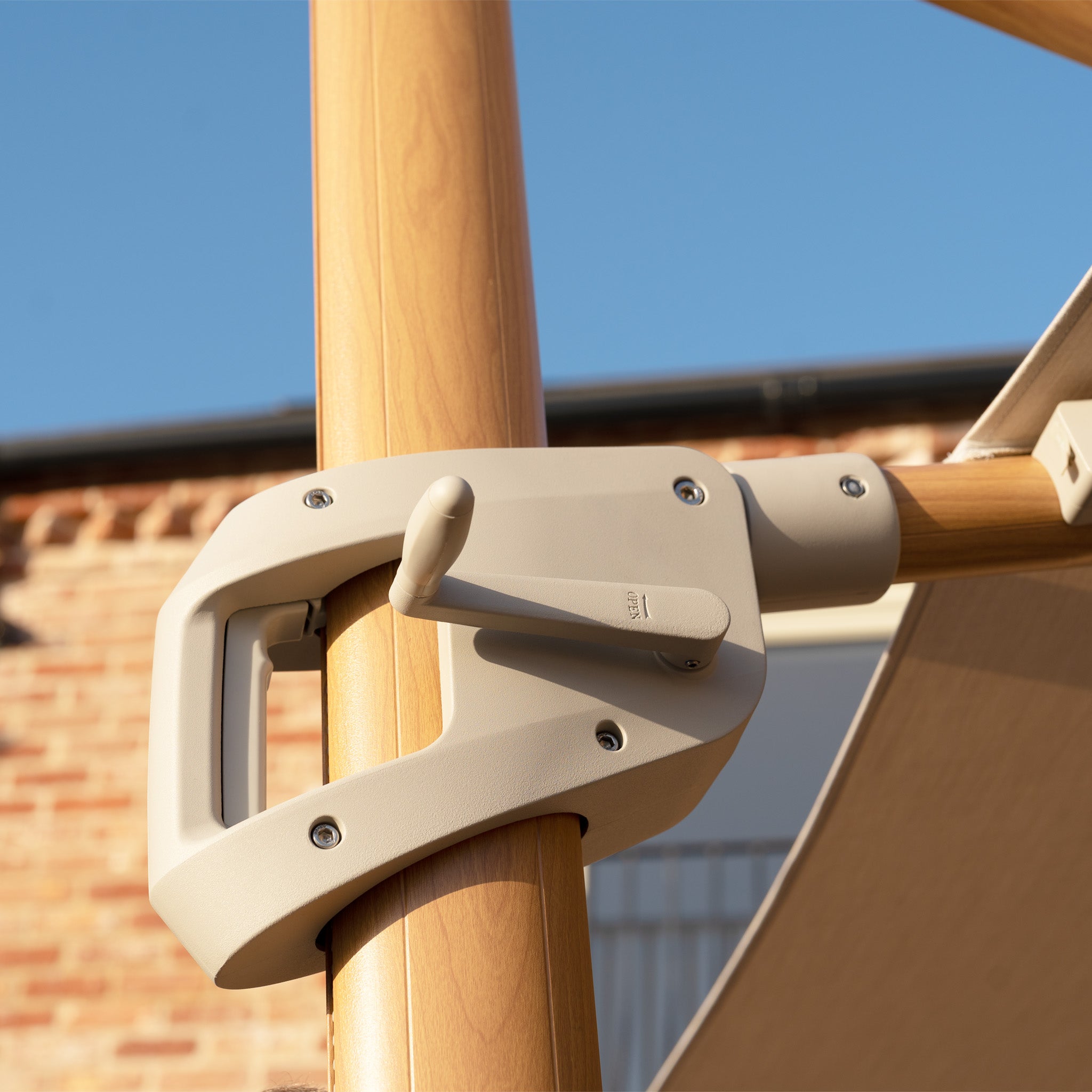 Close-up of the Volos 3m x 4m Rectangular Cantilever Parasol in Wheat with LED lighting and a wood-effect pole, showing the crank handle against a brick wall. Includes a 120kg granite base. UV resistant canopy.
