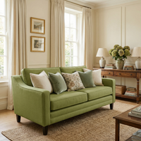 A Wiltshire 2 Seat Sofa in Olive is paired with assorted pillows in a bright, elegant living room with large windows and neutral decor.