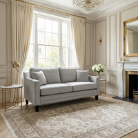 Elegant living room with a Wiltshire 2 Seat Velvet Sofa in Feather Grey, large window, chandelier, and classical neutral-toned decor.