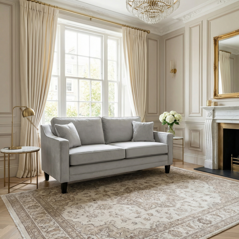 Elegant living room with a Wiltshire 2 Seat Velvet Sofa in Feather Grey, large window, chandelier, and classical neutral-toned decor.