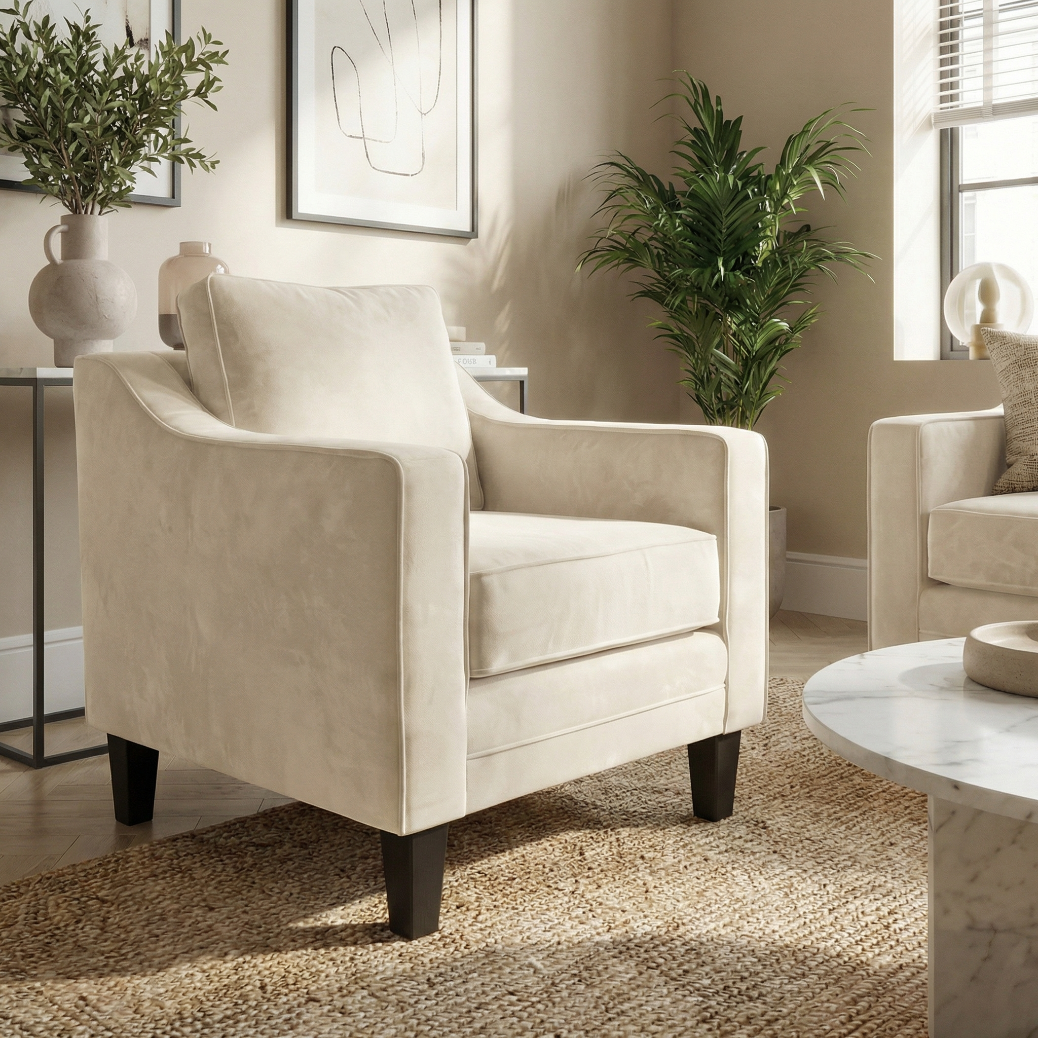 The Wiltshire Velvet Armchair in Cream is handmade in England and featured in a bright, modern living room with plants, art, and a woven rug.