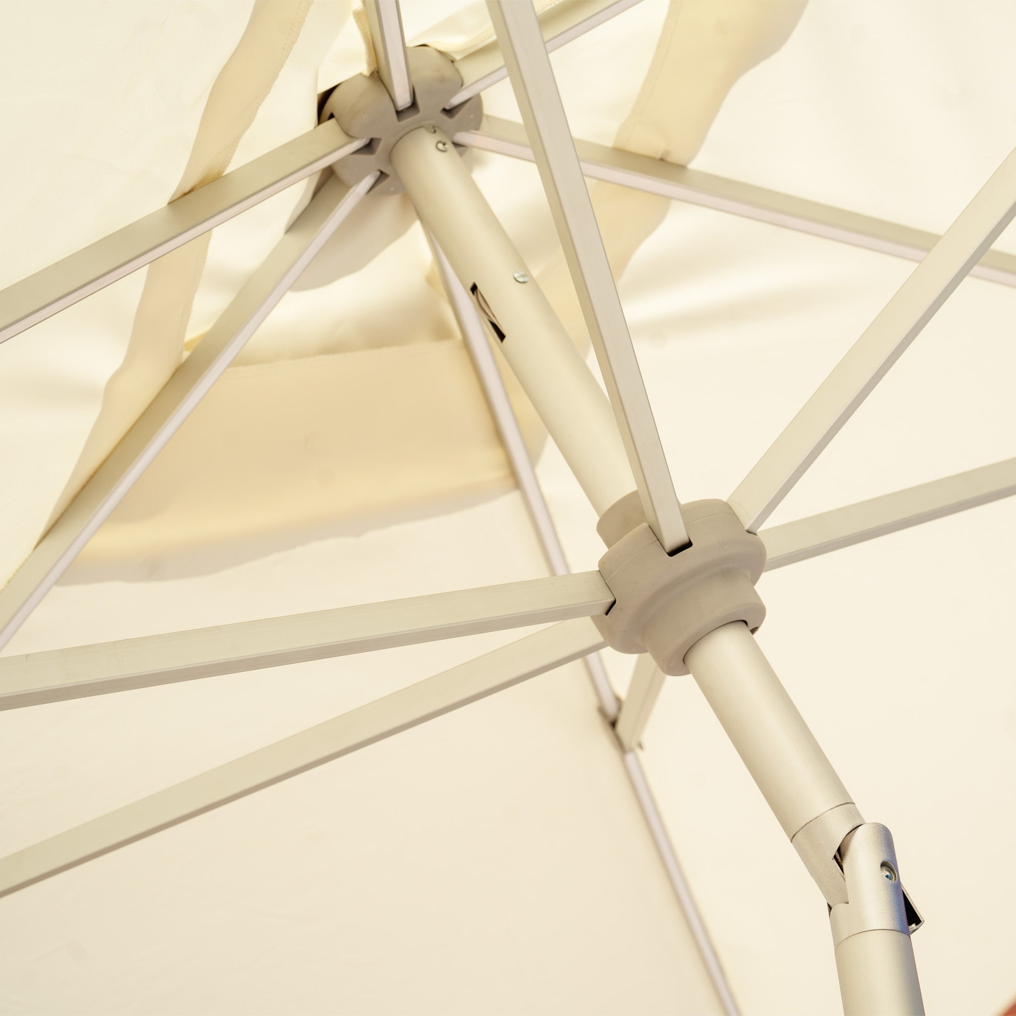 Close-up of the underside of the Zelos 3m x 2m Rectangular Parasol in Cream, highlighting its metal spokes and central pole, elegantly enhanced with integrated LED lighting.