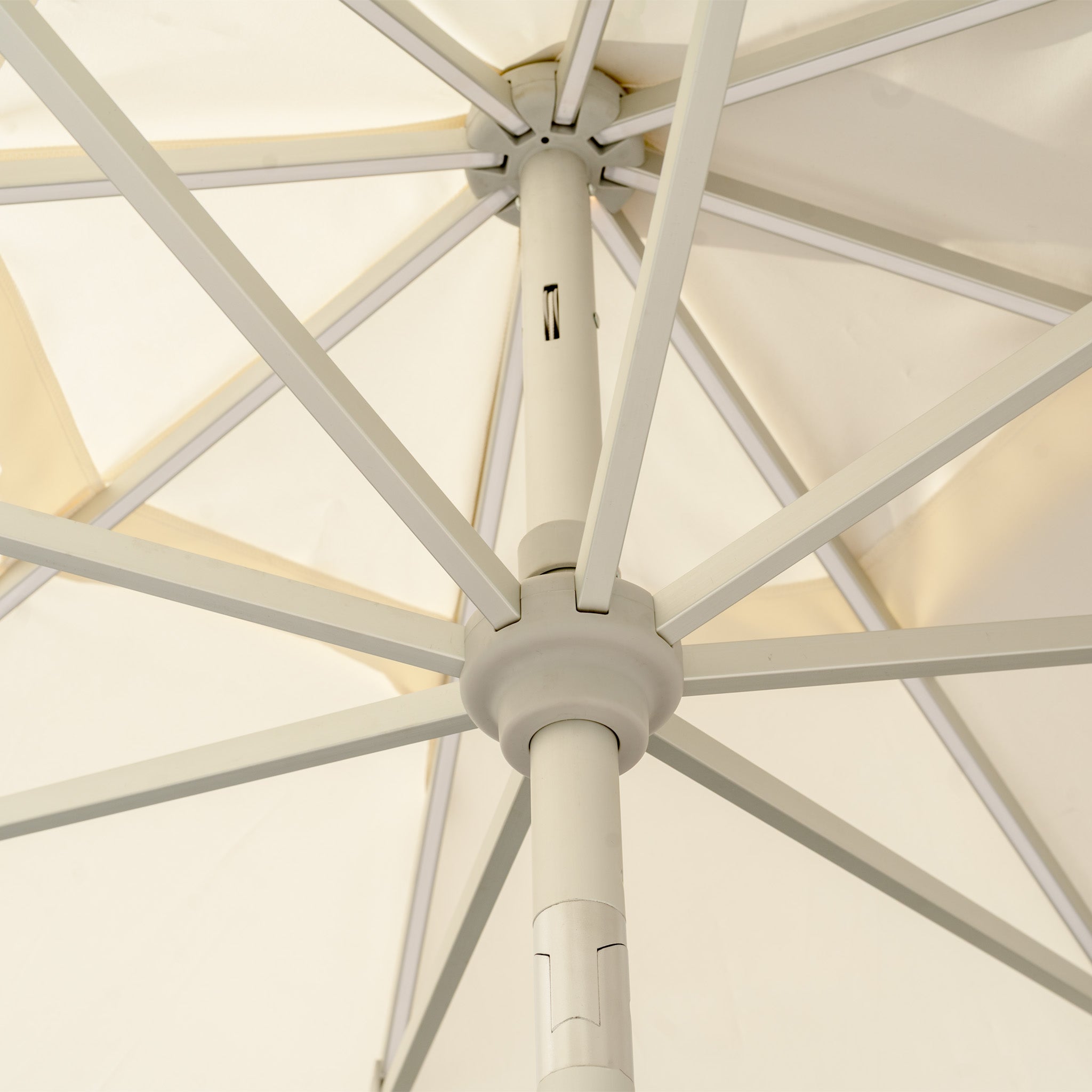 Close-up of the cream support structure and spokes of a Zelos 2.5M Round Parasol with LED Lighting, designed for UV protection and enhancing outdoor living.