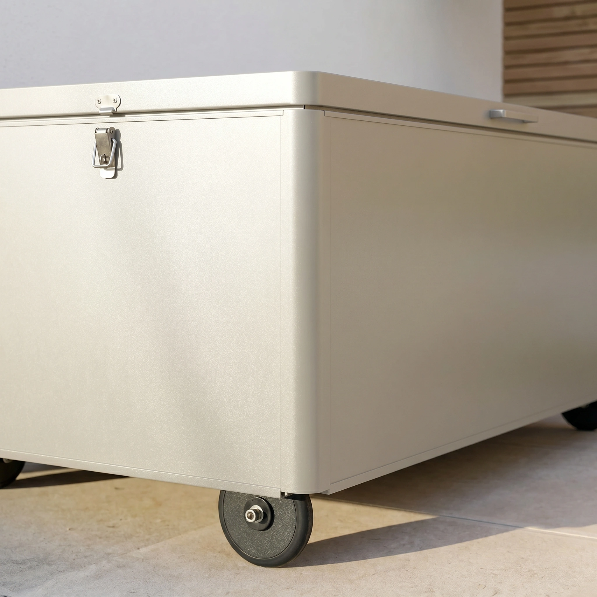 The Large Aluminium Storage Box in Latte, featuring wheels, latch, and handle, rests on a tiled floor—offering durable and secure storage.