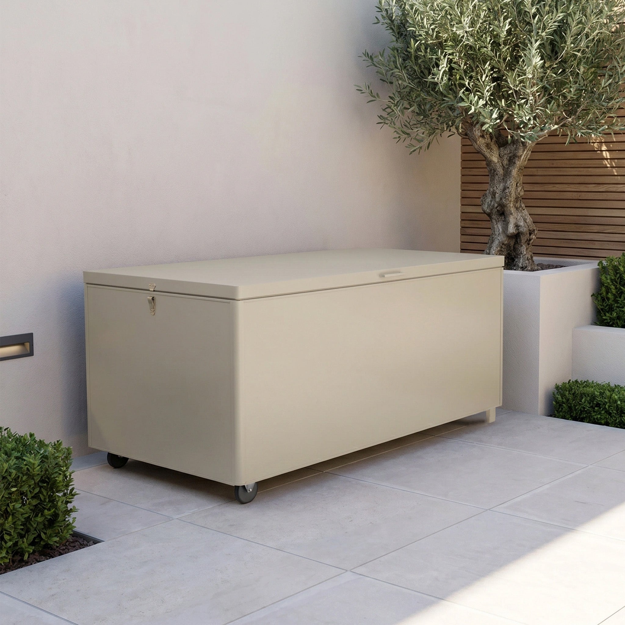 Large Aluminium Storage Box in Latte with wheels on a tiled patio, near an olive tree and green shrubs—perfect as outdoor garden storage for keeping your essentials neat and organized.
