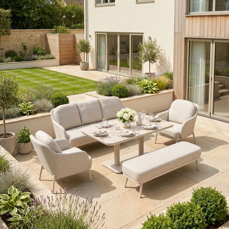 Modern patio with light-toned outdoor garden furniture, featuring the Alva 3 Seat Sofa Dining Set with Rising Table in Fawn, arranged in a lush green backyard under bright sunlight.