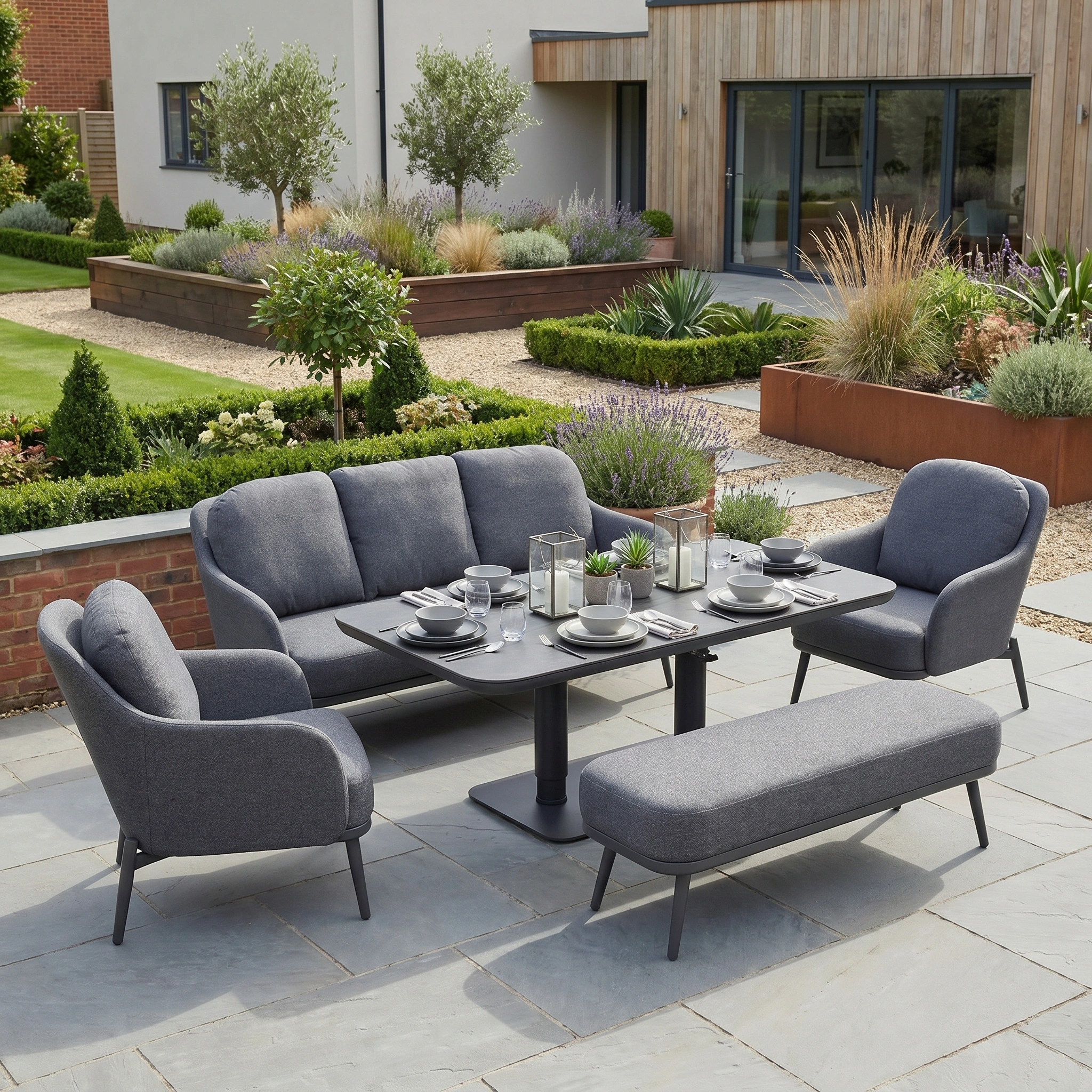 The Alva 3 Seat Sofa Dining Set with Rising Table in Grey features a stylish sofa, chairs, bench, and versatile rising table—ideal for outdoor living on a stone patio in your landscaped garden.
