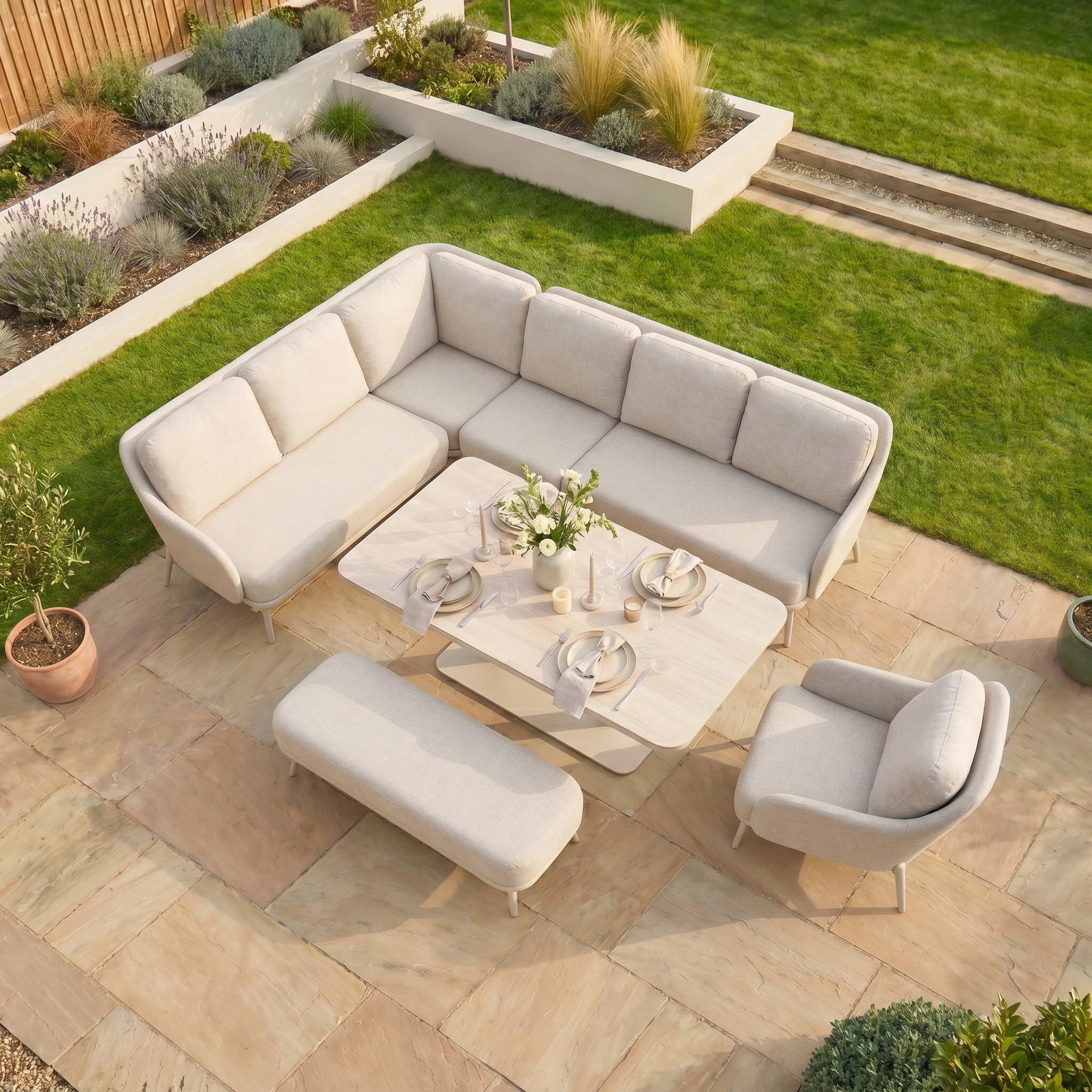The Alva Corner Dining Set with Rising Table and Armchair in Fawn features cream cushions and seats six—ideal garden furniture for relaxed gatherings among lush greenery.