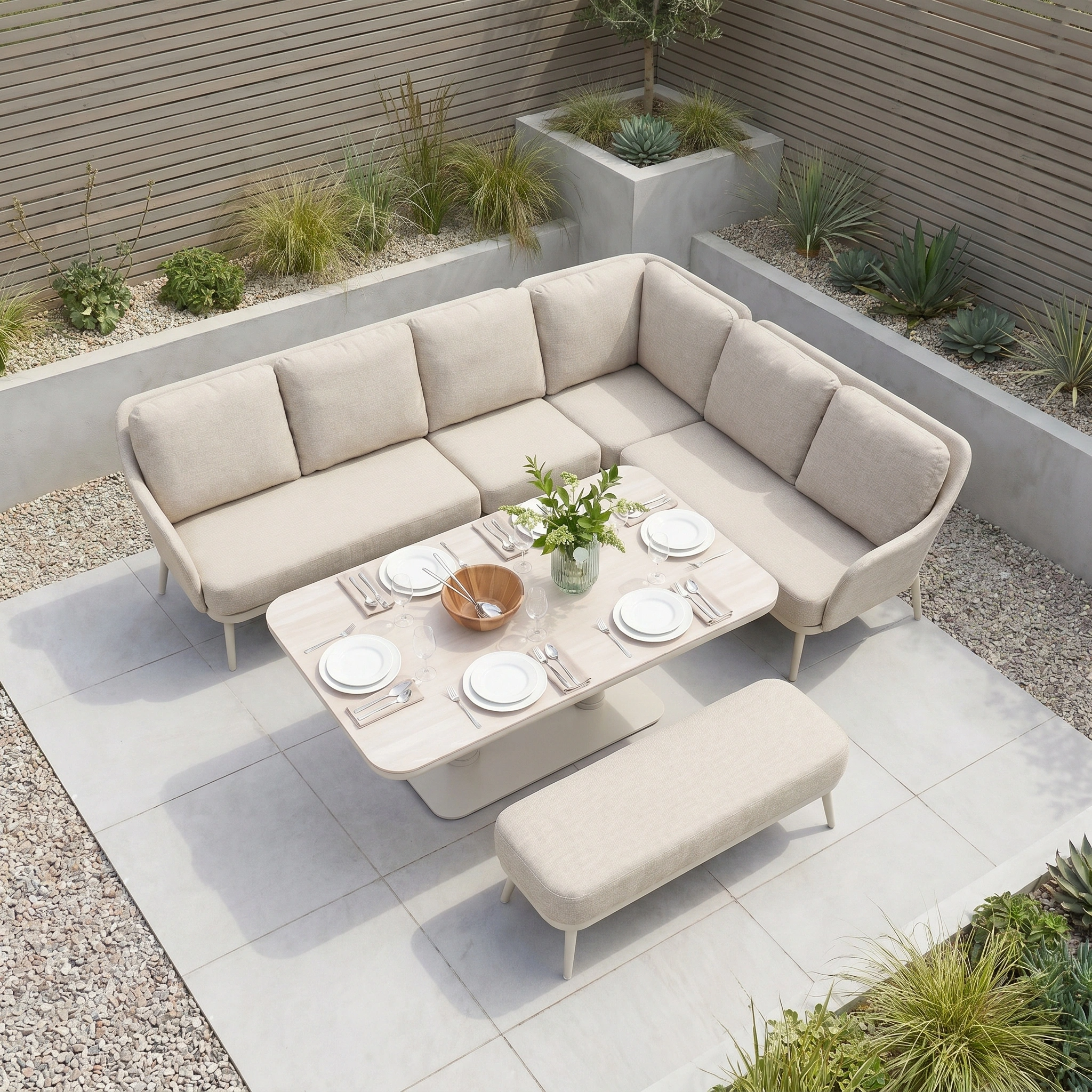 The Alva Corner Dining Set with Rising Table in Fawn features stylish garden furniture, ideal for a modern patio and perfect for dining with plates, glasses, and a centerpiece.