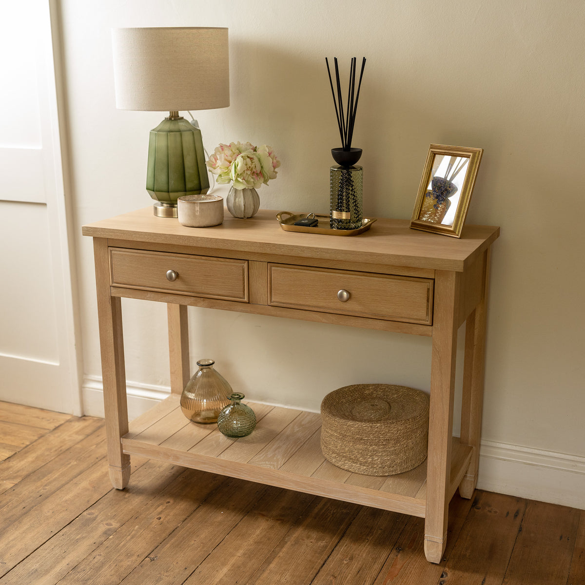 Amberley 2 Drawers Console Table in Light Oak, styled with a lamp, flowers, photo frame, and vases.