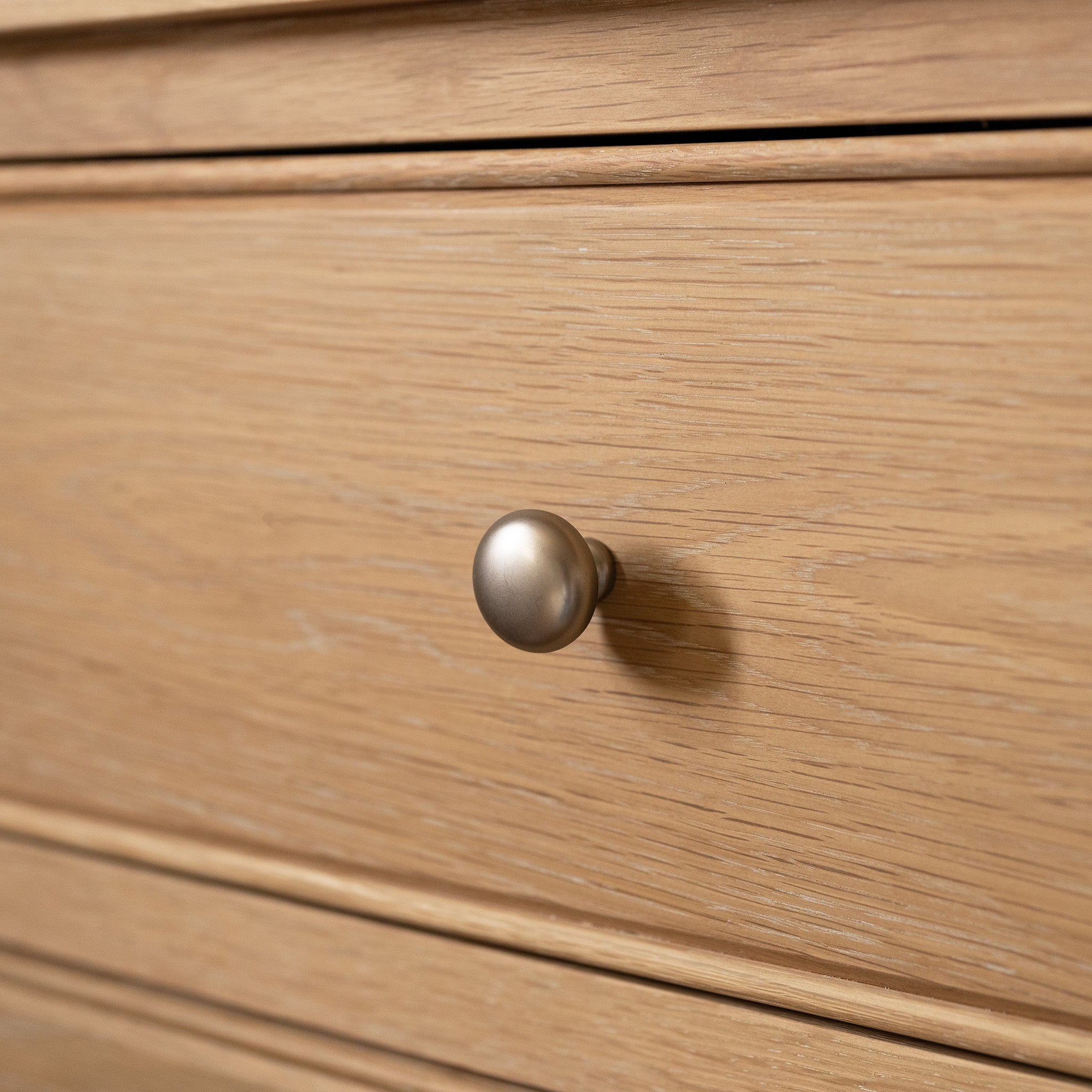 Close-up of the Amberley 3 Chest of Drawers in Light Oak, featuring a round silver knob and visible wood grain—a simple, stylish design perfect for bedroom storage.