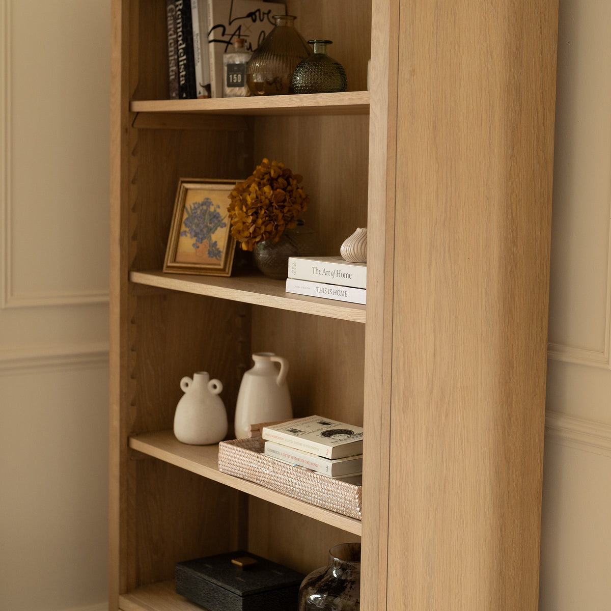 Amberley Large Bookcase in Light Oak, featuring neatly arranged books, vases, framed art, and decorative objects on its spacious shelves, brings a touch of modern country charm to your space.