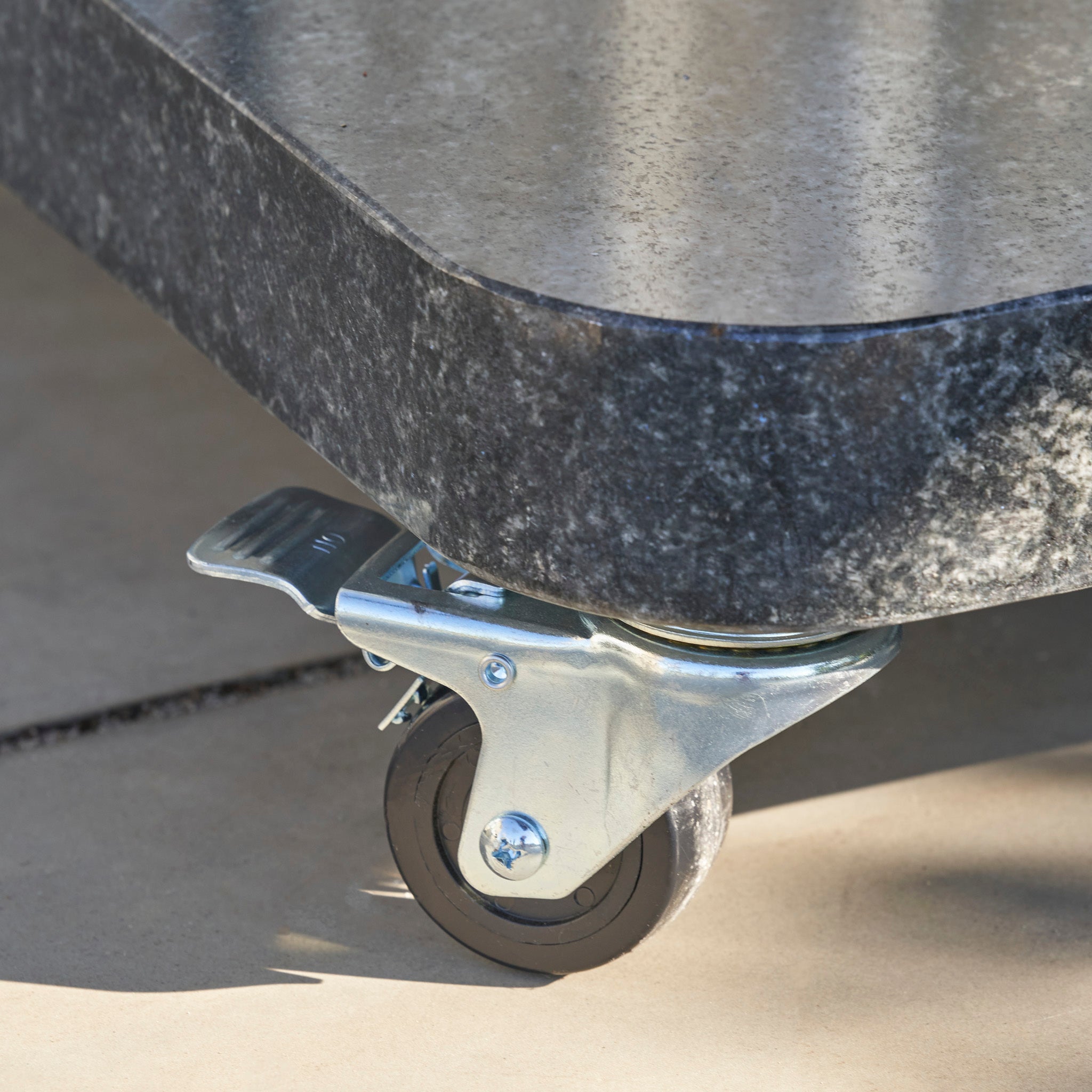 Close-up of the Ancona 90kg Granite Base with Wheels, featuring a metal caster with brake, resting on a tiled floor.