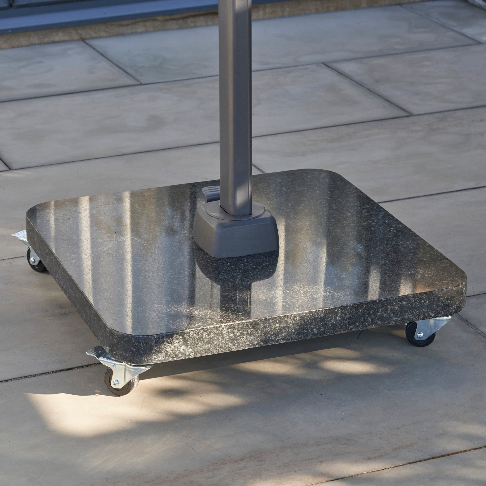 Ancona 90kg Granite Base with Wheels on a stone patio.