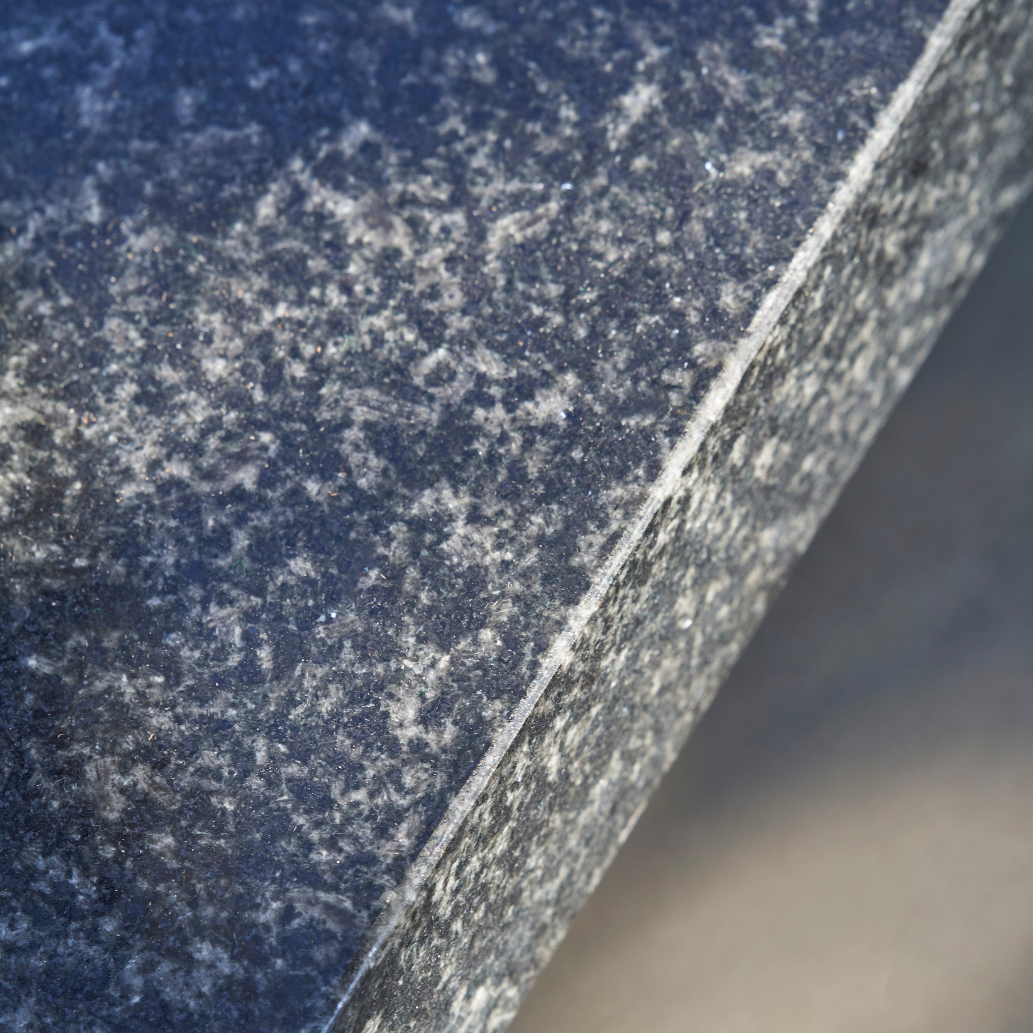 Close-up of the Ancona 90kg Granite Base with Wheels, highlighting its polished, speckled granite surface and beveled edge.