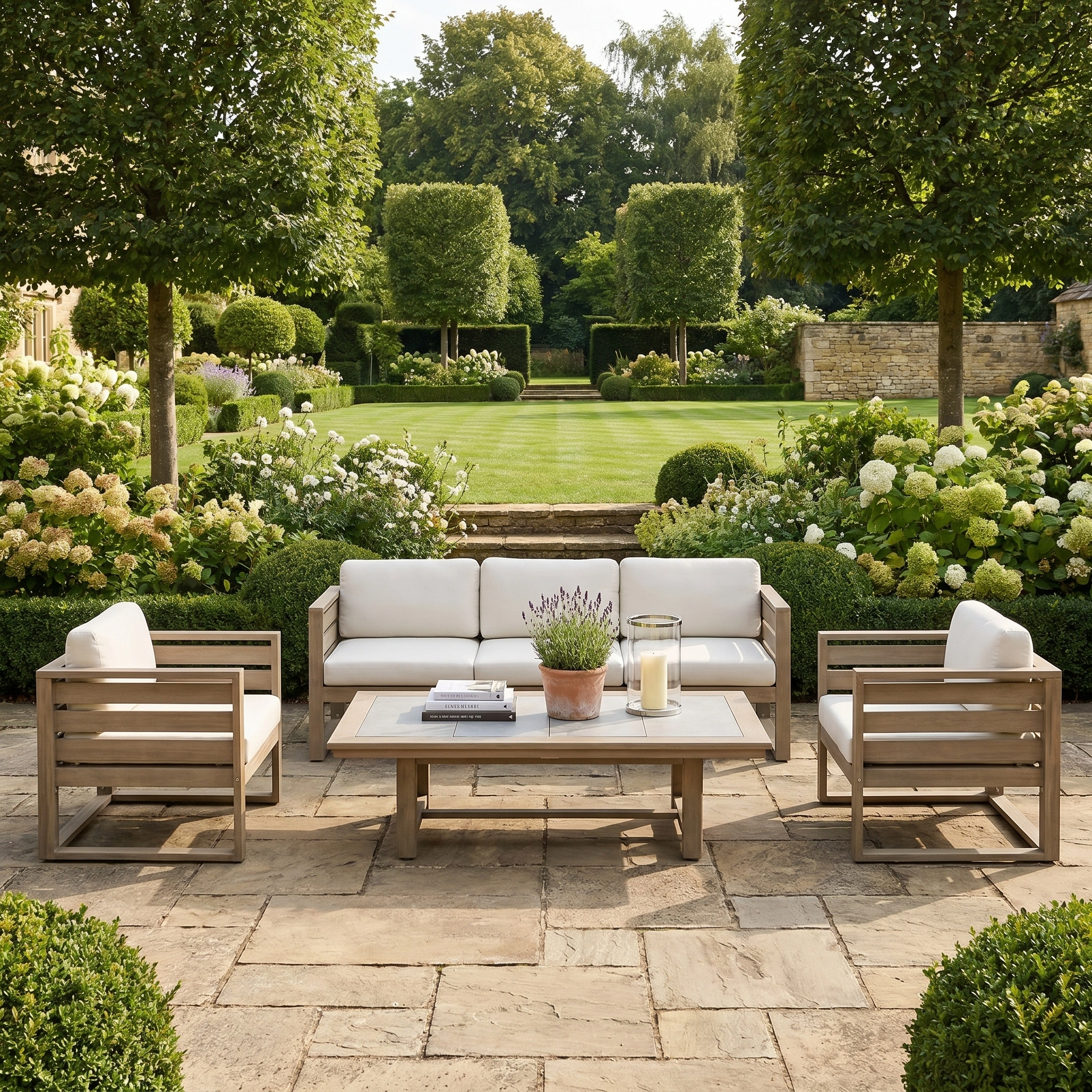 Outdoor patio with the Andora 3 Seat Sofa Set with 2 in 1 Table in Weathered Brown, featuring white cushions and set amid lush green gardens and blooming flowers.