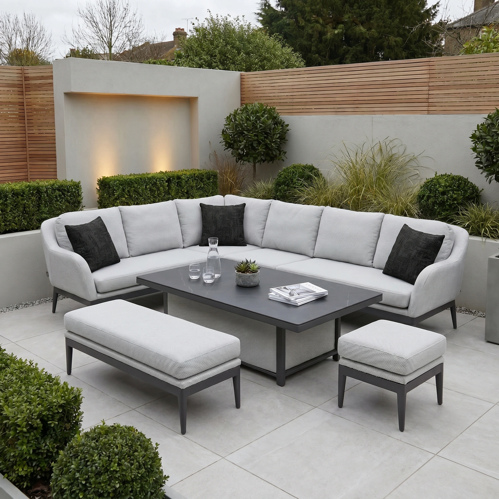 Modern patio with a gray sectional, table, bench, and plants in a landscaped garden, styled with outdoor scatter cushions including the Agora Artisan Grafito Medium Scatter Cushion (45cm x 45cm) for extra comfort.