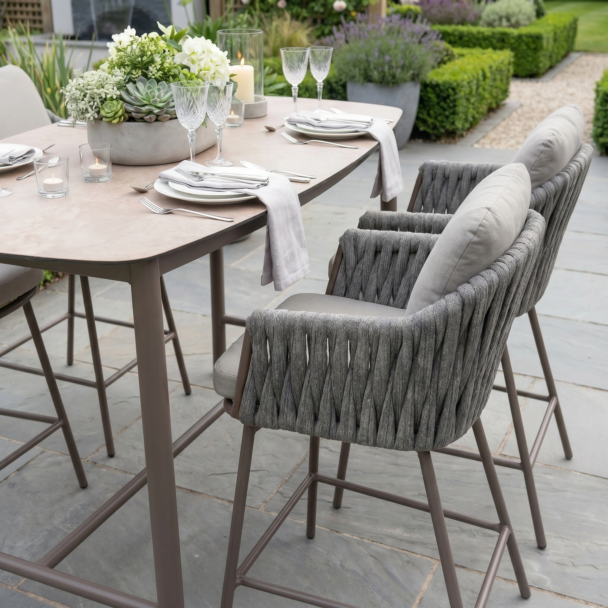 The Capri 4 Seat High Rectangular Dining Set in Stone Grey features woven stools and a chic table—perfect for stylish outdoor gatherings.