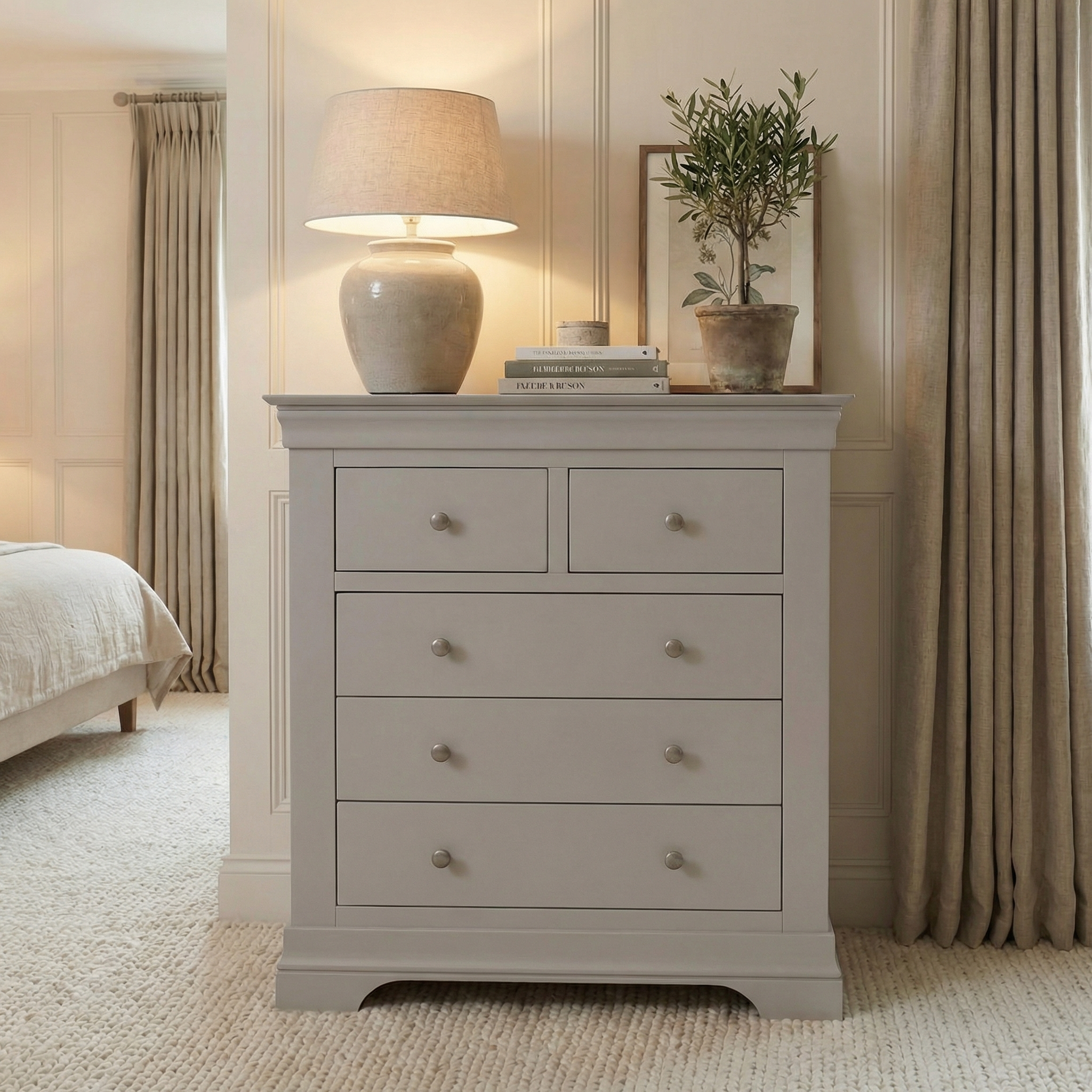 The Chalbury 2 Over 3 Chest of Drawers in Pebble Grey features five spacious drawers and a stylish top, perfect for adding cozy charm to your bedroom—great for displaying lamps, books, or plants.