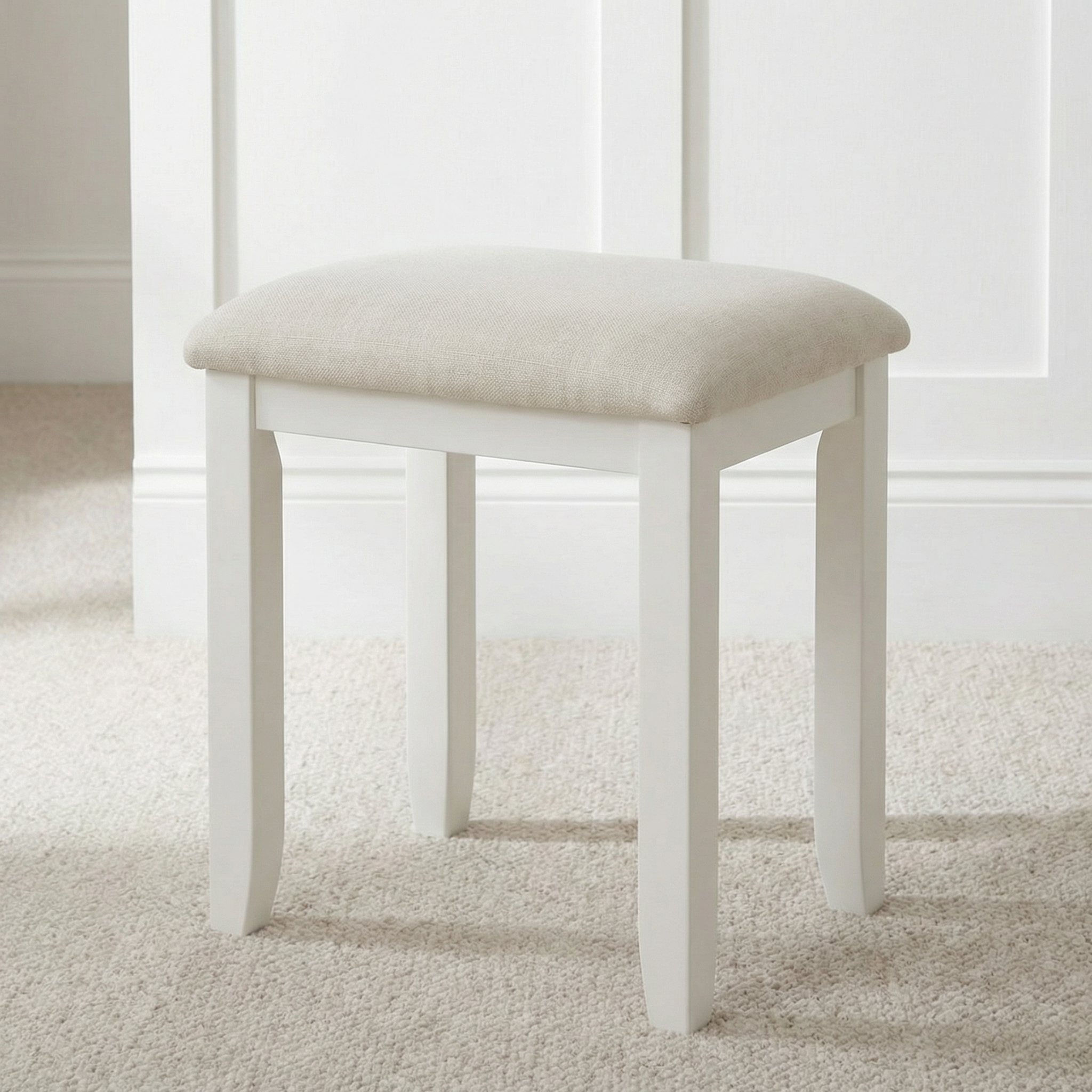 The Chalbury Stool in Warm White features a built-in cushion and adds an elegant touch when placed on a light carpeted floor.