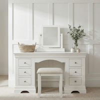 White vanity with stool, basket, eucalyptus in a vase, and the Chalbury Mirror in Warm White against a paneled wall.