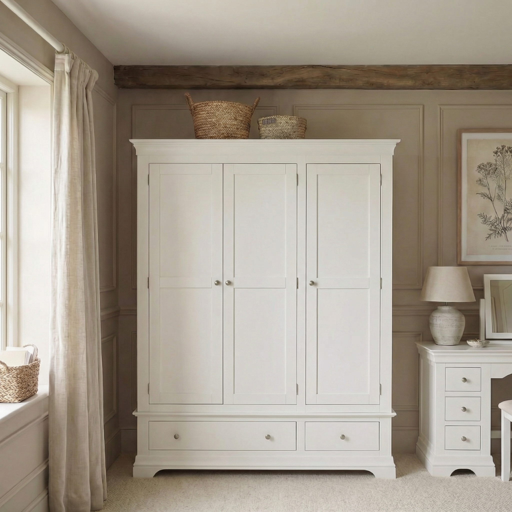 The Chalbury Triple Wardrobe in Warm White with baskets on top, placed beside a matching nightstand with a lamp, provides stylish bedroom storage in a neutral-toned room.