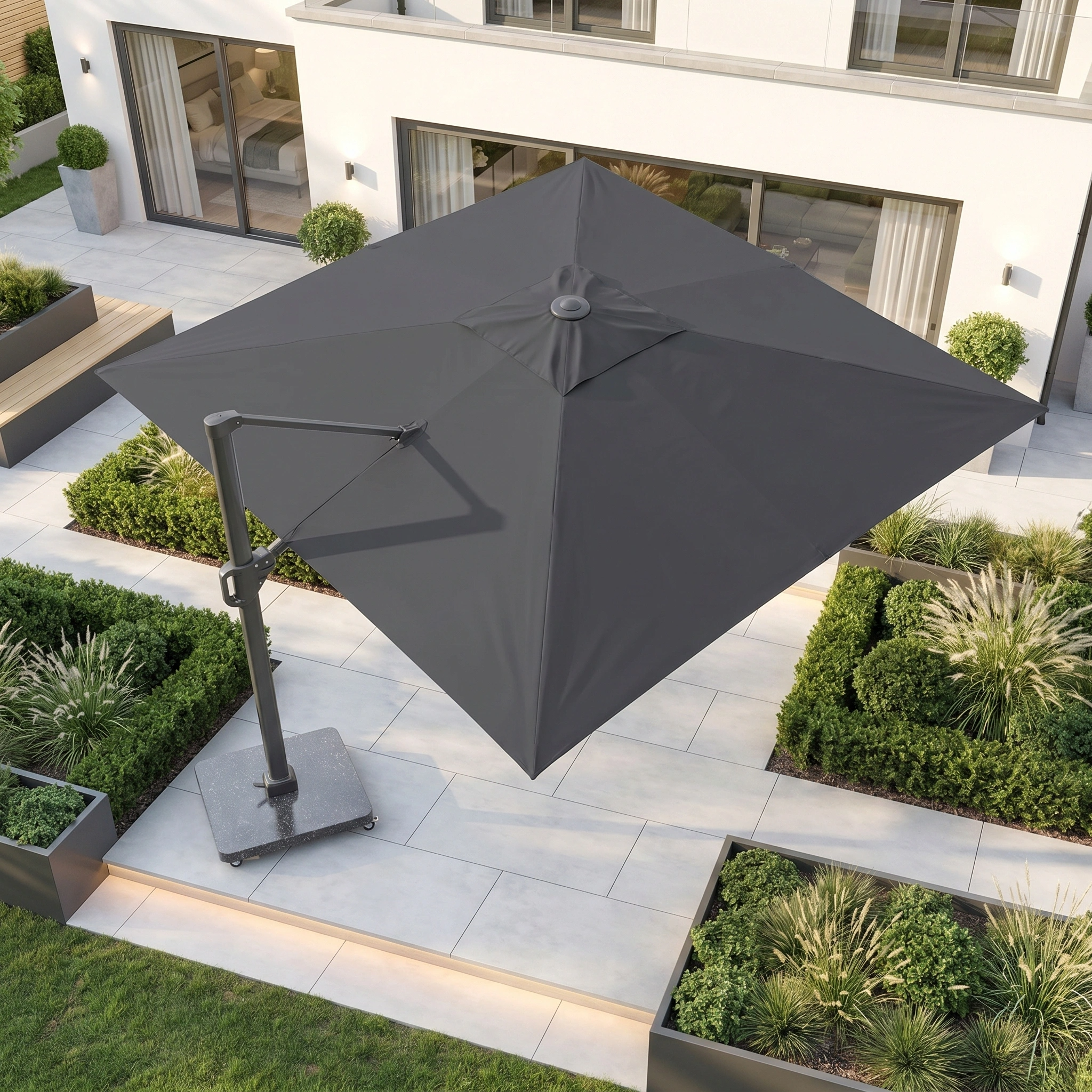 The Challenger T2 3.5m x 2.6m Rectangular Cantilever Parasol in Anthracite with 90kg Granite Base provides UV protection over a modern tiled garden, surrounded by green plants and outdoor seating.