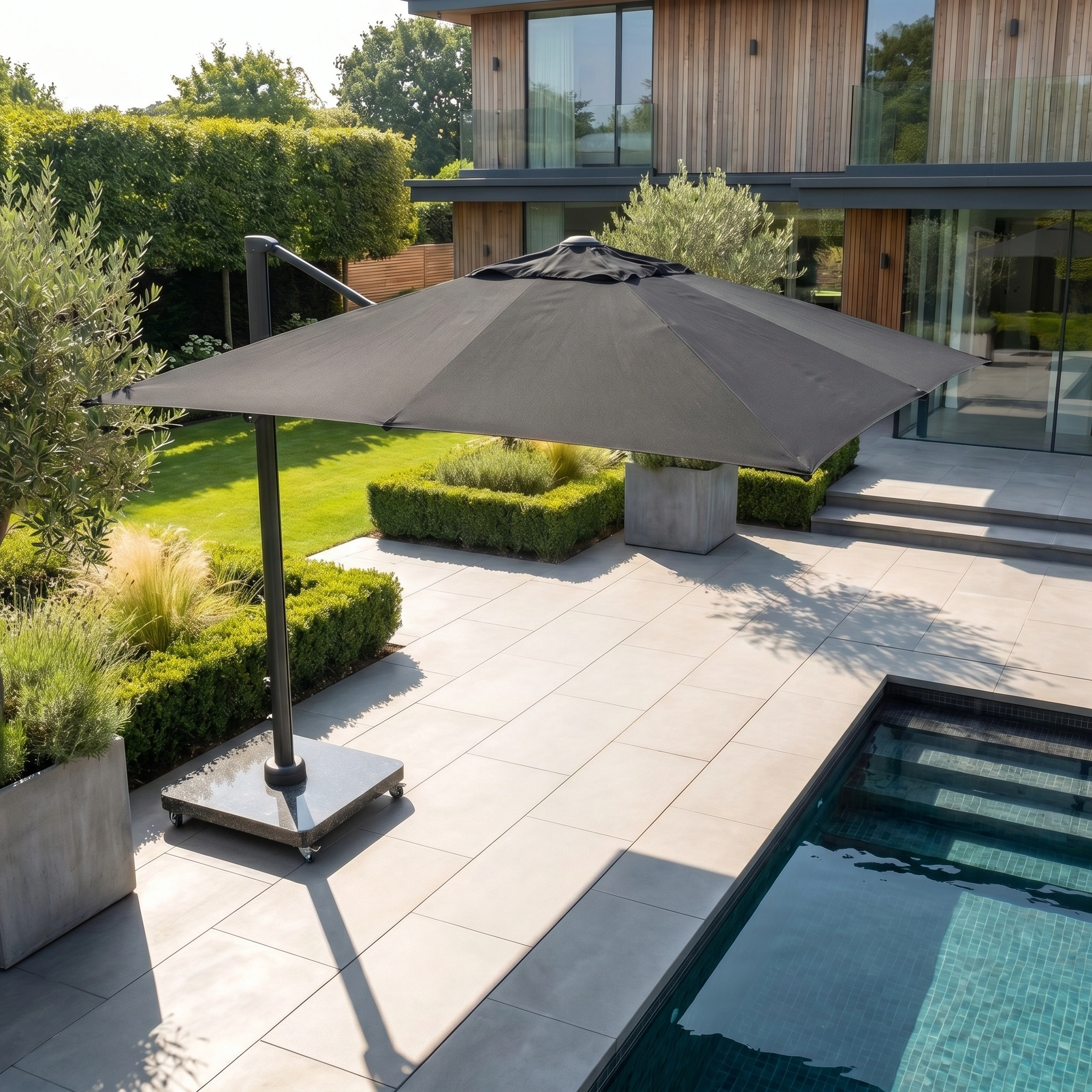 The Challenger T2 Premium 3.5m x 2.6m Rectangular Cantilever Parasol in Black provides shade for a modern poolside patio in a landscaped backyard.