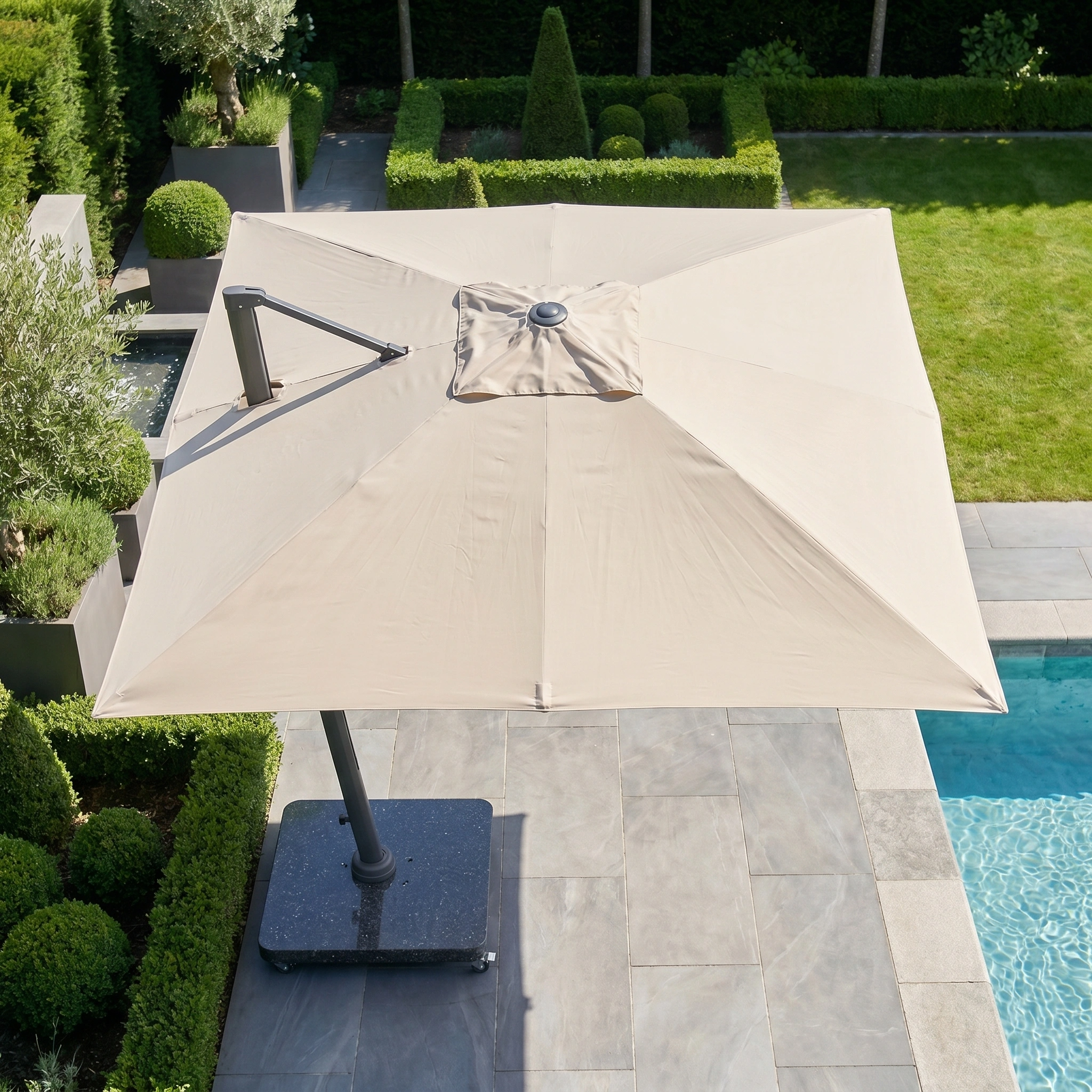 The Challenger T2 Premium 3.5m x 2.6m Rectangular Cantilever Parasol in Champagne offers elegant outdoor shade by the pool, blending beautifully with neatly trimmed garden hedges.