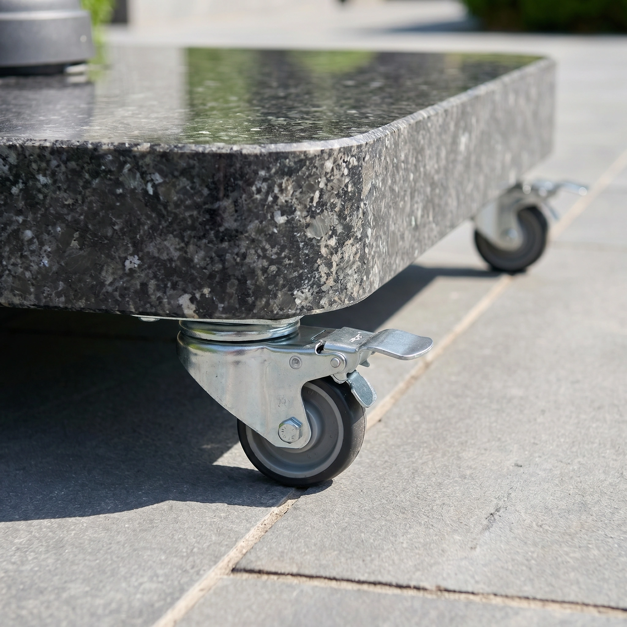 Close-up of a granite slab on metal caster wheels with brakes, set on outdoor tiles—an ideal base for the Challenger T2 Premium 3.5m x 2.6m Rectangular Cantilever Parasol in Champagne, ensuring stable and secure outdoor shade.