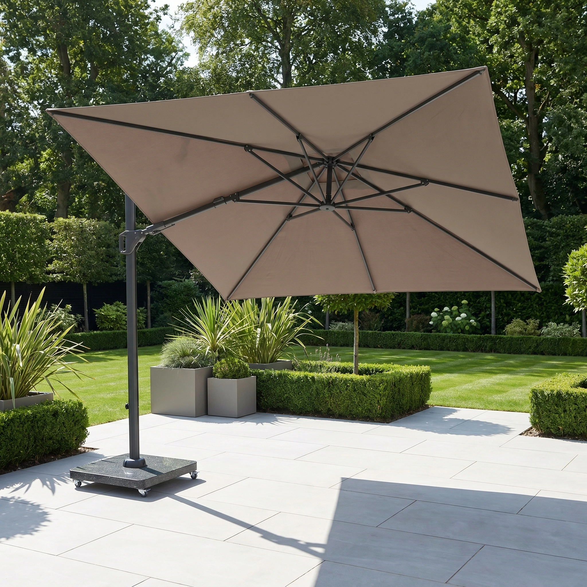 The Challenger T2 Premium 3.5m x 2.6m Rectangular Cantilever Parasol in Deep Taupe stands open on a tiled terrace, providing ample outdoor shade amid lush green plants and a manicured lawn.