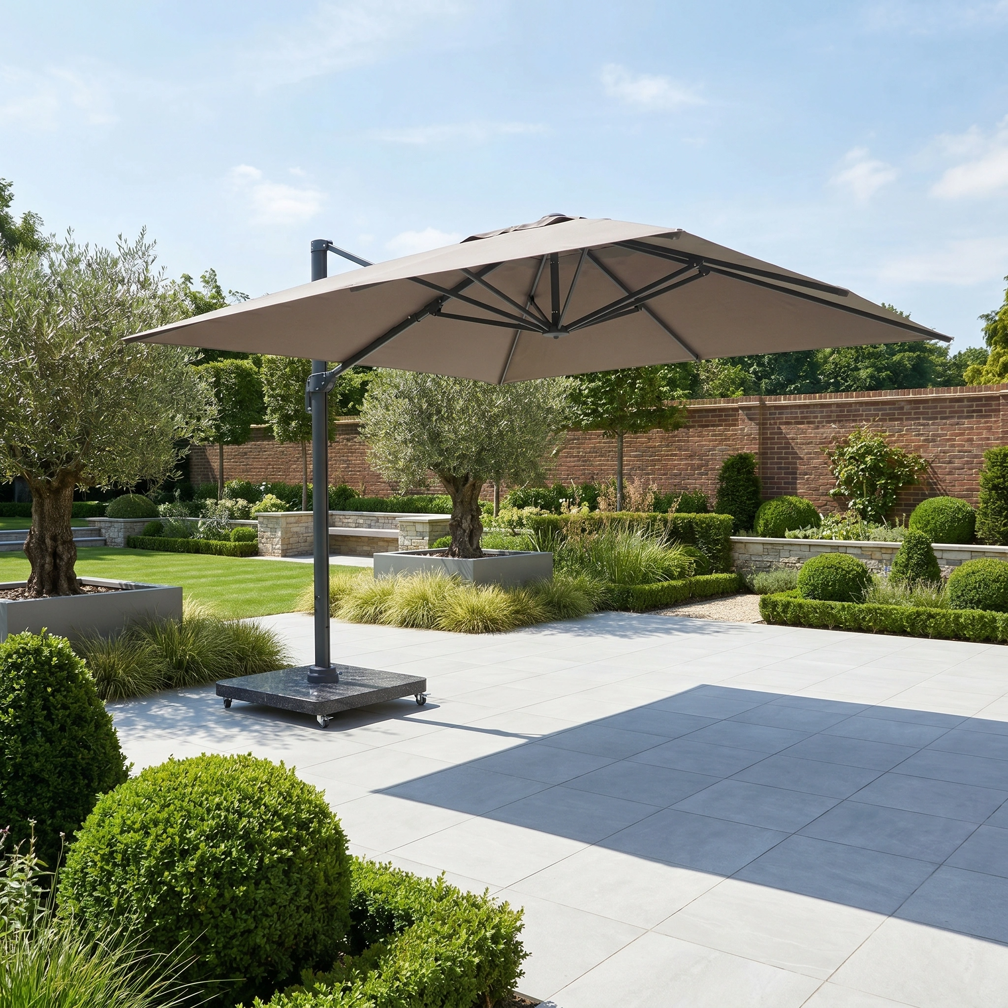 The Challenger T2 Premium 3.5m x 2.6m Rectangular Cantilever Parasol in Deep Taupe shades a tiled terrace in a landscaped garden with manicured shrubs and trees.