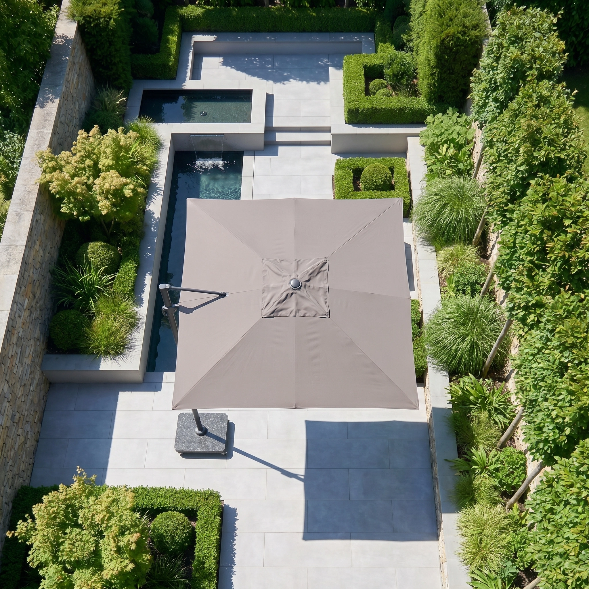 Aerial view of a modern garden patio with the Challenger T2 Premium 3.5m x 2.6m Rectangular Cantilever Parasol in Deep Taupe providing outdoor shade, surrounded by lush green landscaping.