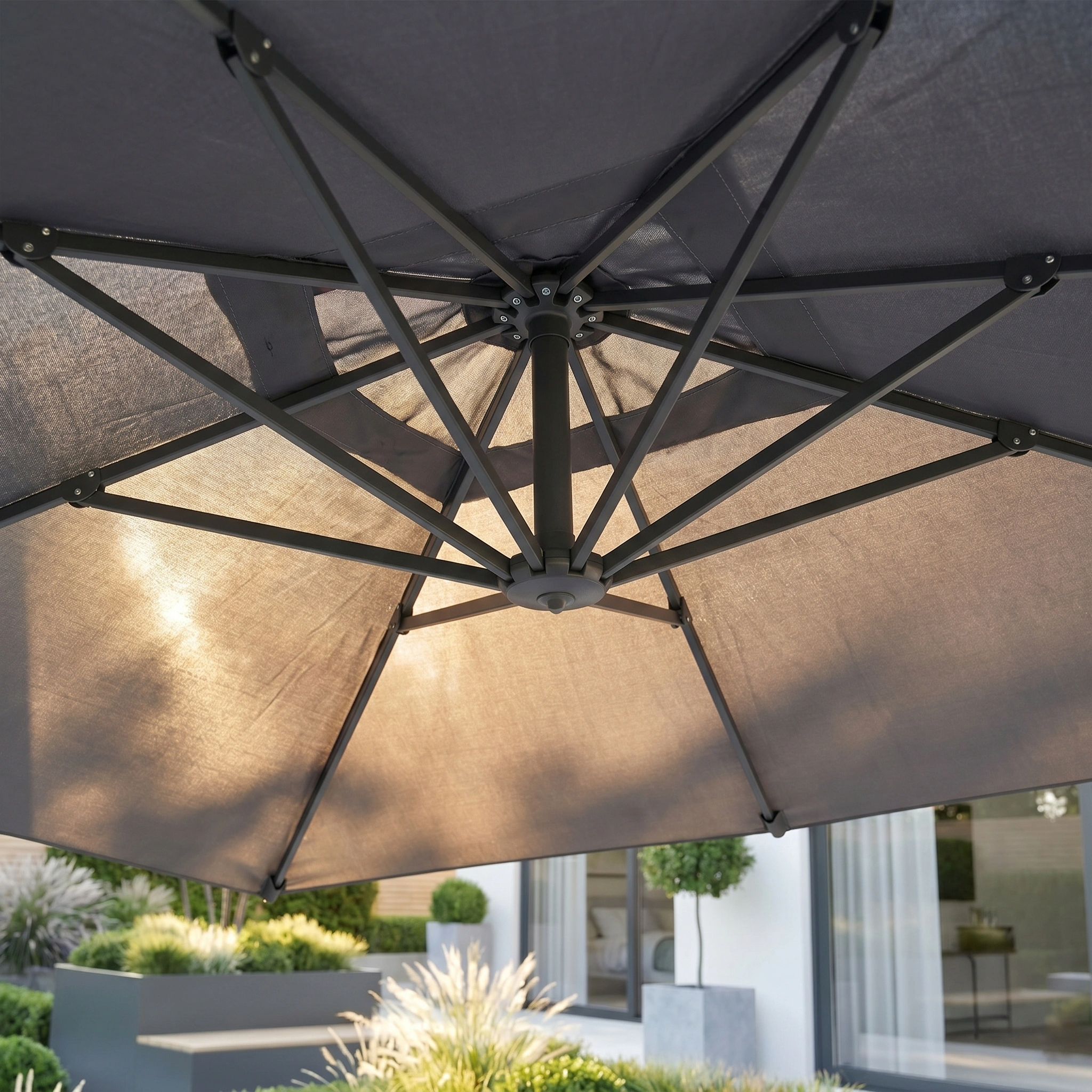 Close-up of the Challenger T2 3.5m x 2.6m Rectangular Cantilever Parasol in Anthracite with UV protection and powder-coated aluminium, shown outdoors with its 90kg granite base and a garden and house in the background.
