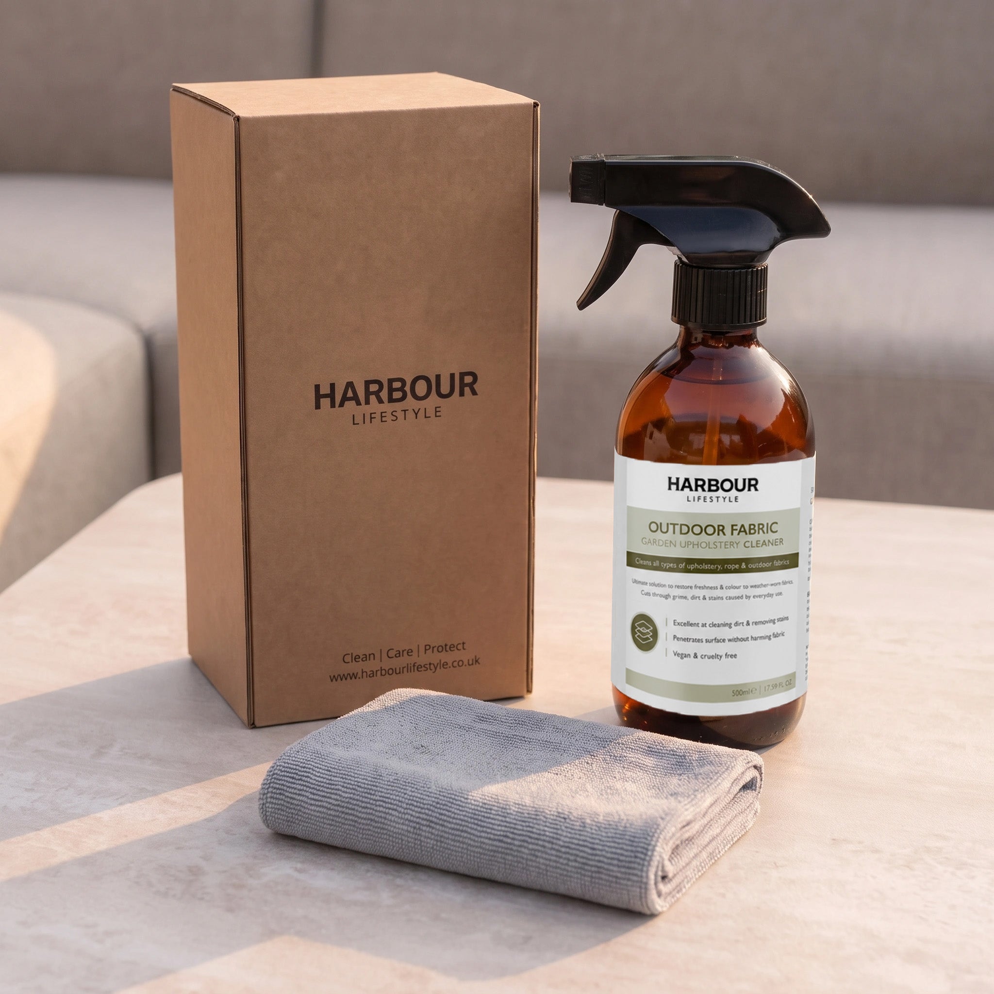 An Outdoor Furniture Cushion, Rope and Upholstery Cleaner, along with a cloth and box, are displayed on a table.