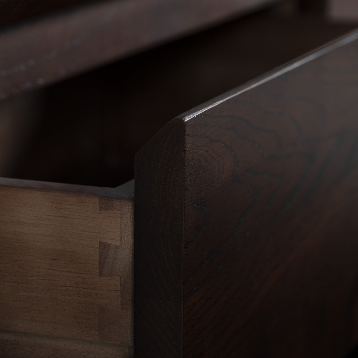 Close-up of a dark walnut drawer partially open in an Oslo TV Unit in Walnut, showing dovetail joints on the lighter wood side.
