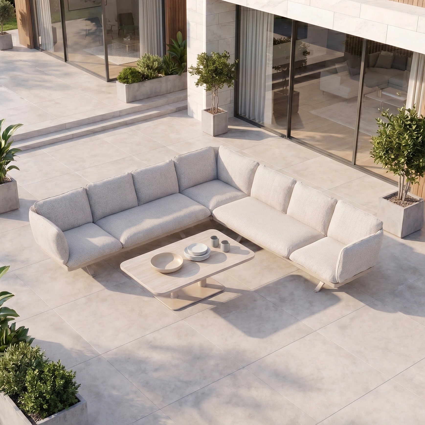 Modern patio featuring the Como Corner Sofa Set with Altura Rising Table in Oatmeal—a sleek sectional and adjustable table, complemented by potted plants on tiled flooring—ideal for outdoor luxury living.