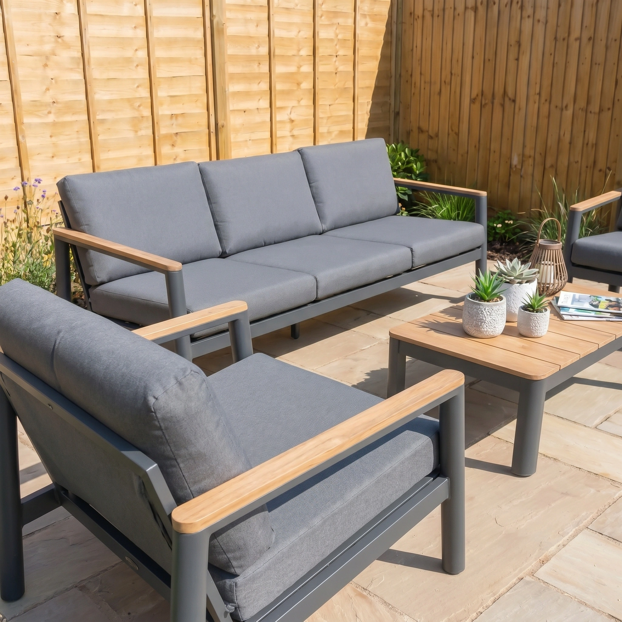 The Cora 3 Seat Sofa Set in Grey features plush cushions, a coffee table, and is perfect as weather resistant garden furniture for relaxing outdoors on your terrace.