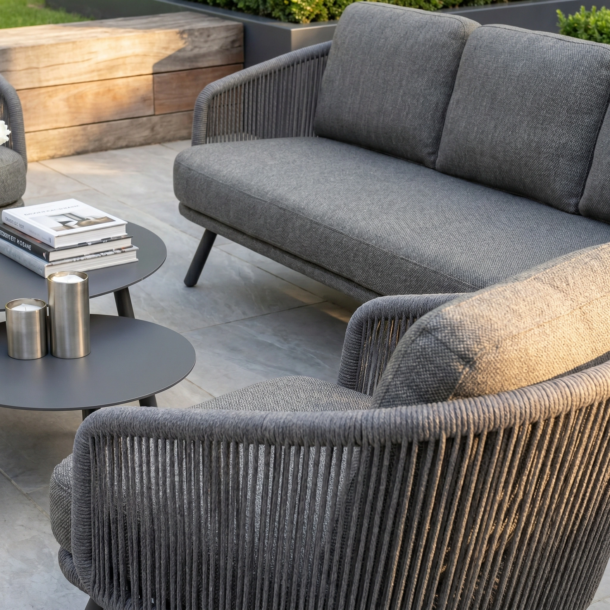 Modern outdoor patio with the Dekota 3 Seat Rope Sofa Set in charcoal, featuring matching coffee tables and a footstool, arranged on a tiled floor.