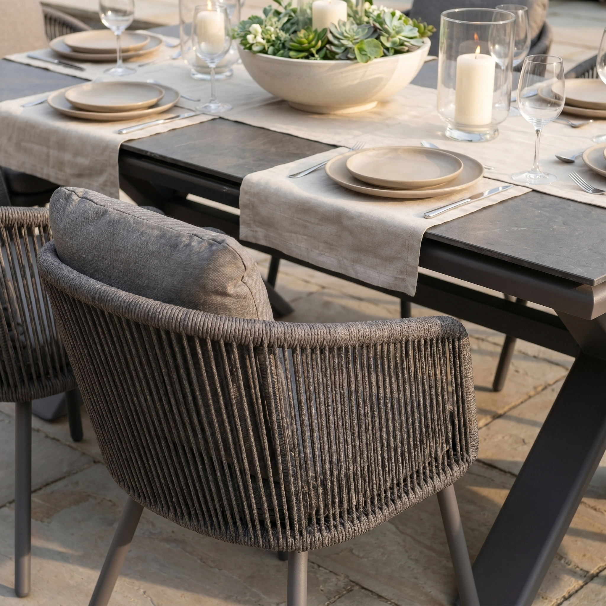 Outdoor dining set with neutral plates, glassware, candles, and a succulent centerpiece arranged on the Dekota 6 Seat Rope Dining Set with Albatross Extending Table in Charcoal—perfect for stylish gatherings.