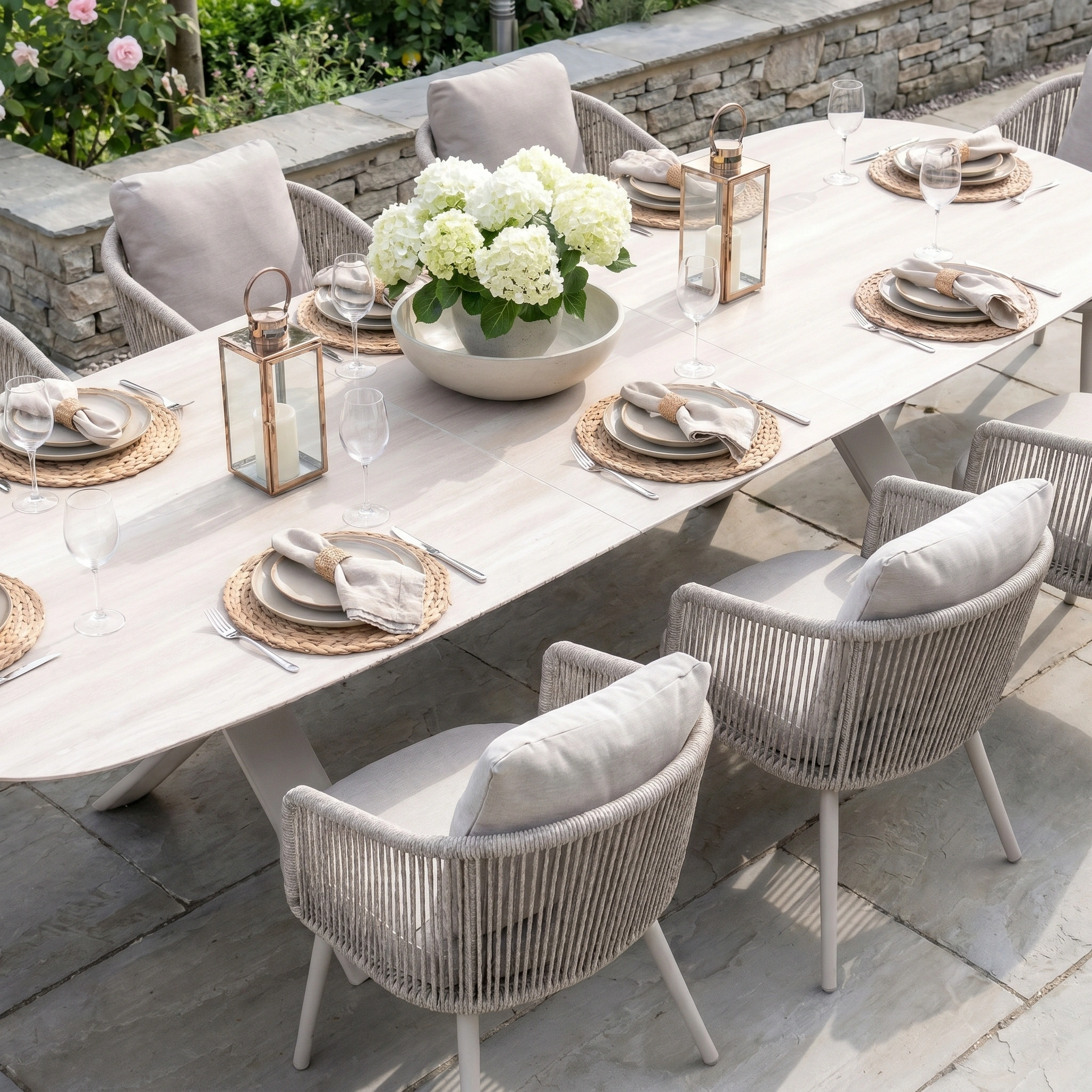 The Dekota 8 Seat Oval Rope Dining Set with Albatross Extending Table in Fawn is ideal for outdoor gatherings, especially when styled with white hydrangeas and lanterns.