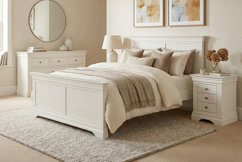 Neatly made bed in a bedroom with white furniture and decor.