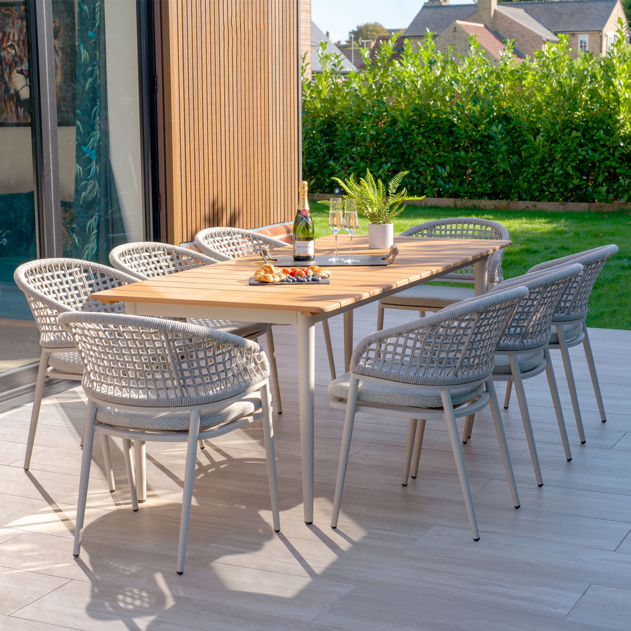 The Kalama 8 Seat Rectangular Dining Set with Teak Table in Latte features a beautiful teak table and eight woven chairs, ideal for outdoor gatherings. Enjoy wine and appetizers under a sunny sky, with weatherproof aluminum accents providing both durability and style.
