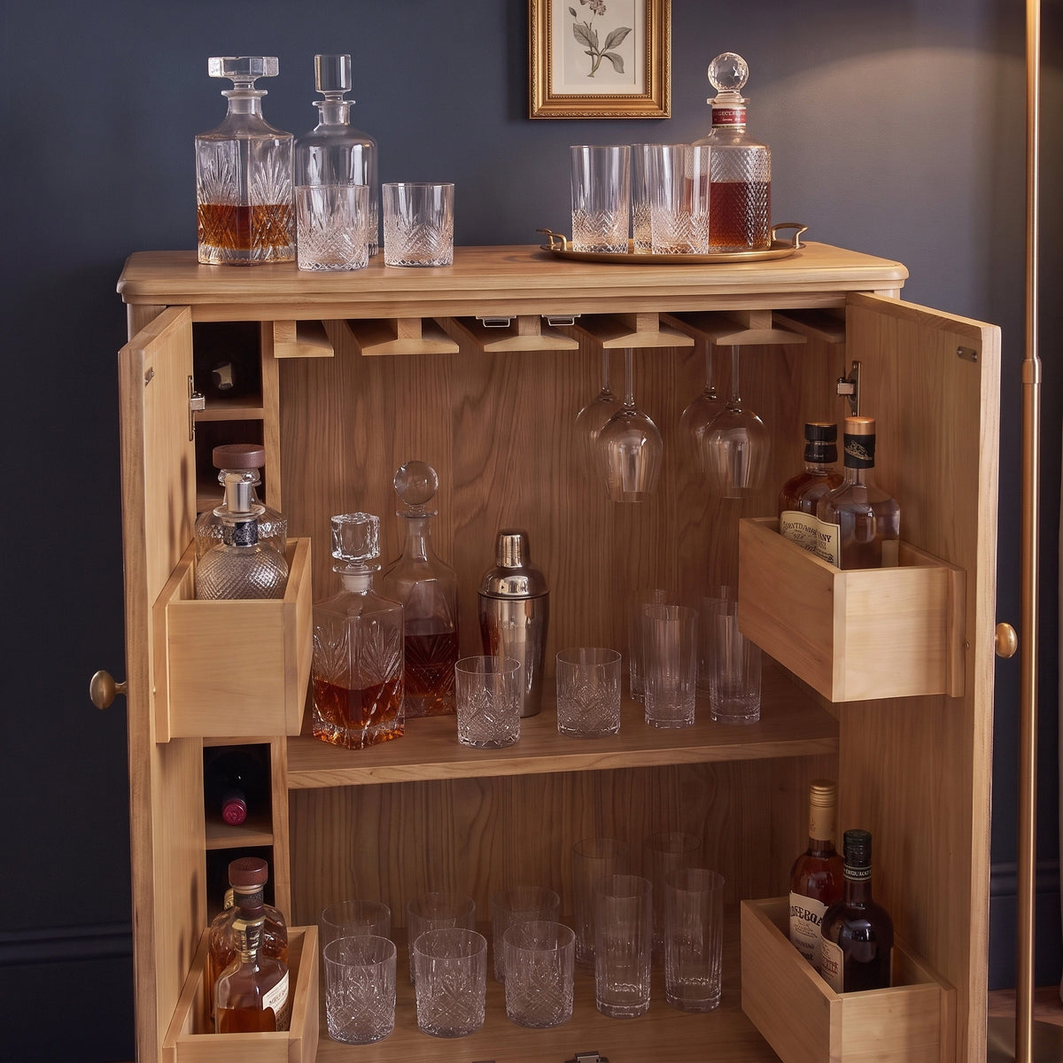 The Hadley Herringbone Drinks Cabinet in Natural is shown open, displaying bottles, decanters, glasses, and cocktail accessories inside—making it the perfect stylish home bar cabinet or a stunning centerpiece for your entertaining space.