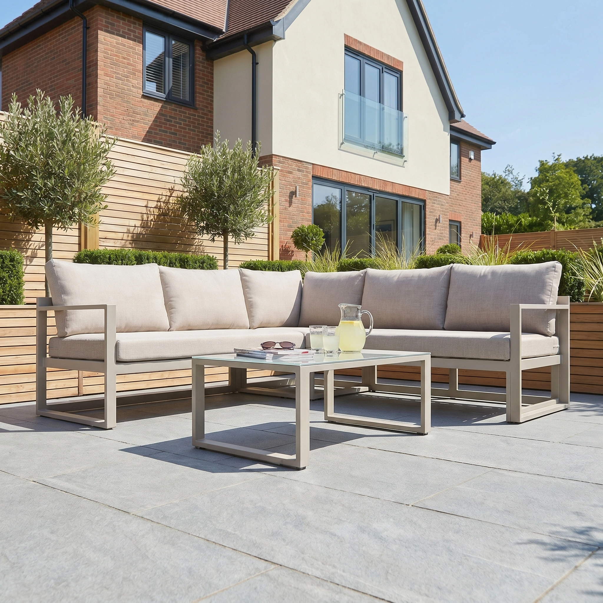 Modern patio with the Havana Corner Group Set featuring latte-colored reclining seats and a coffee table, perfectly arranged in a serene garden setting.