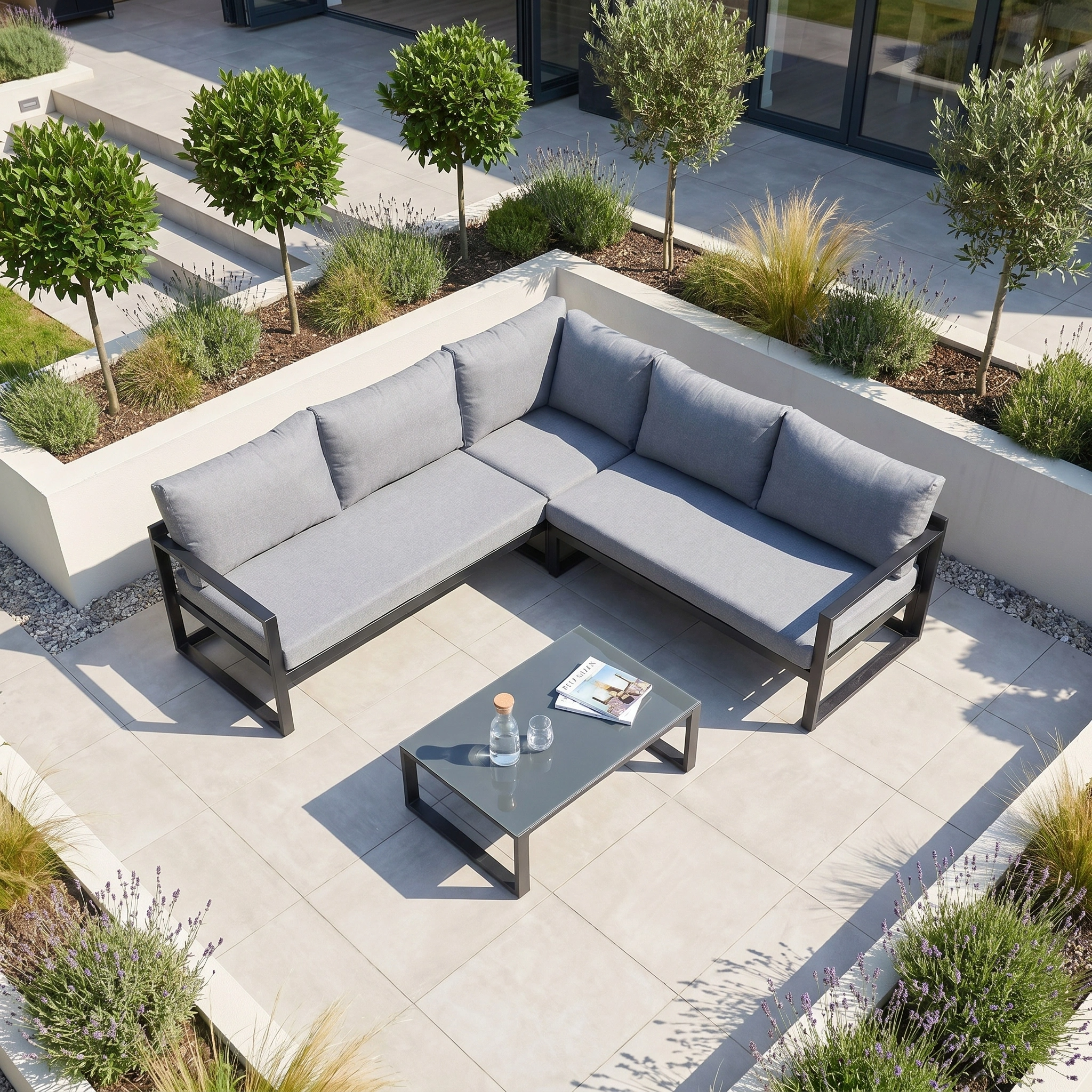 Modern outdoor patio featuring the Havana Corner Group Set with Reclining Feature and Coffee Table in Washed Grey, plus landscaped plants in raised beds.