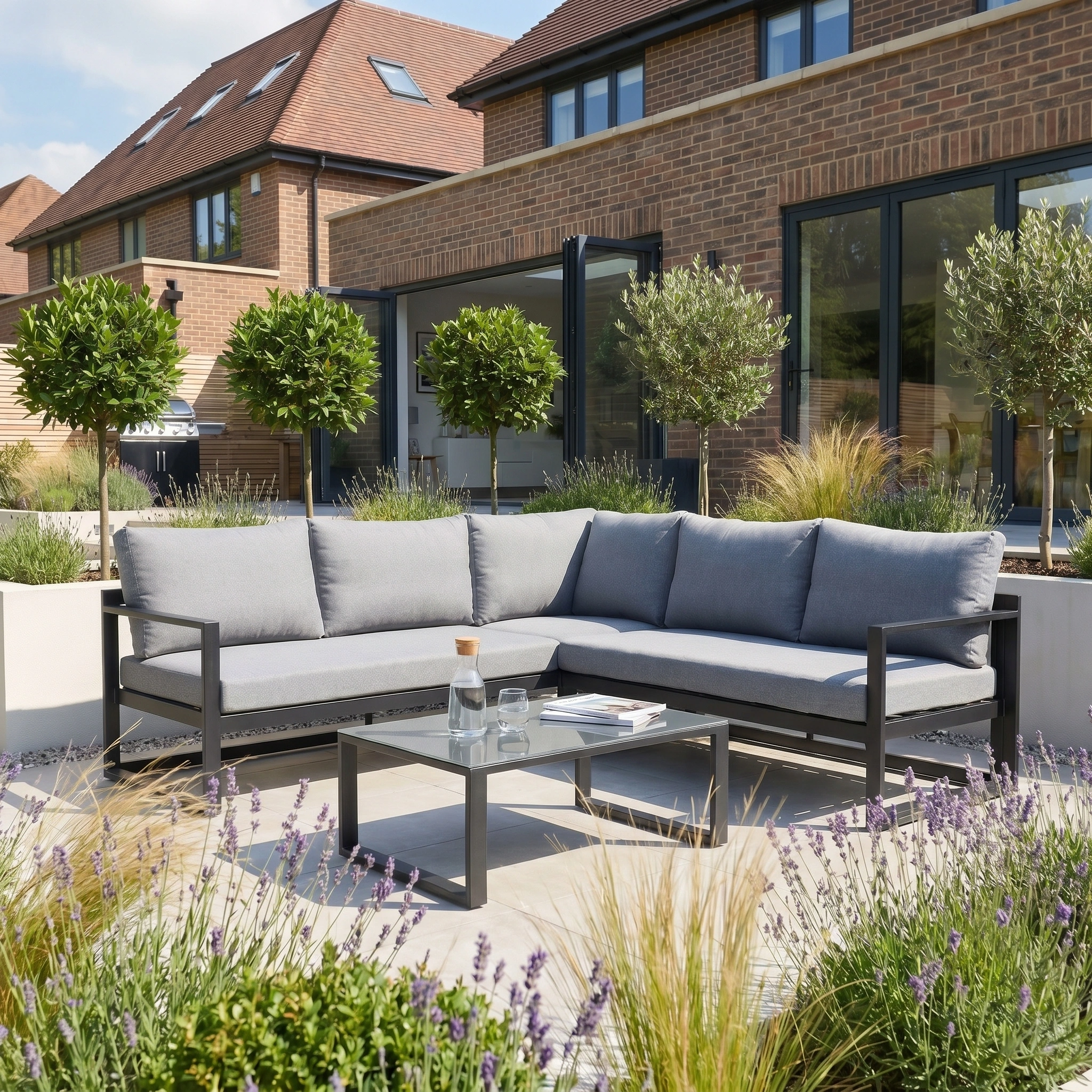 Modern outdoor patio with the Havana Corner Group Set featuring a reclining function and a coffee table in washed grey, complemented by lush greenery in a sunny backyard garden.